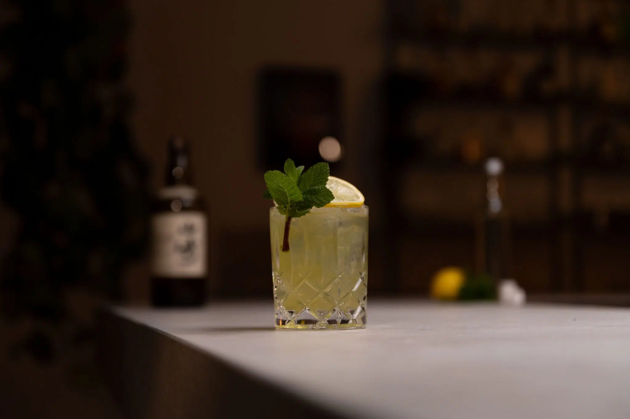 Japanese whiskey, lemon, sugar syrup, sugar cubes and mint laid out on a white bar table