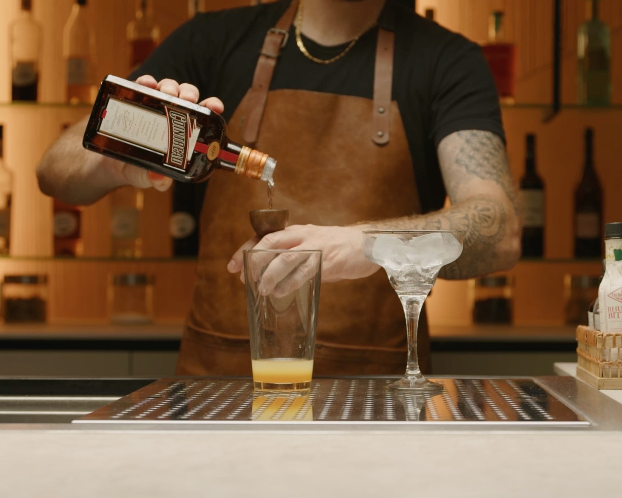 Orange liqueur poured into shaker with jigger