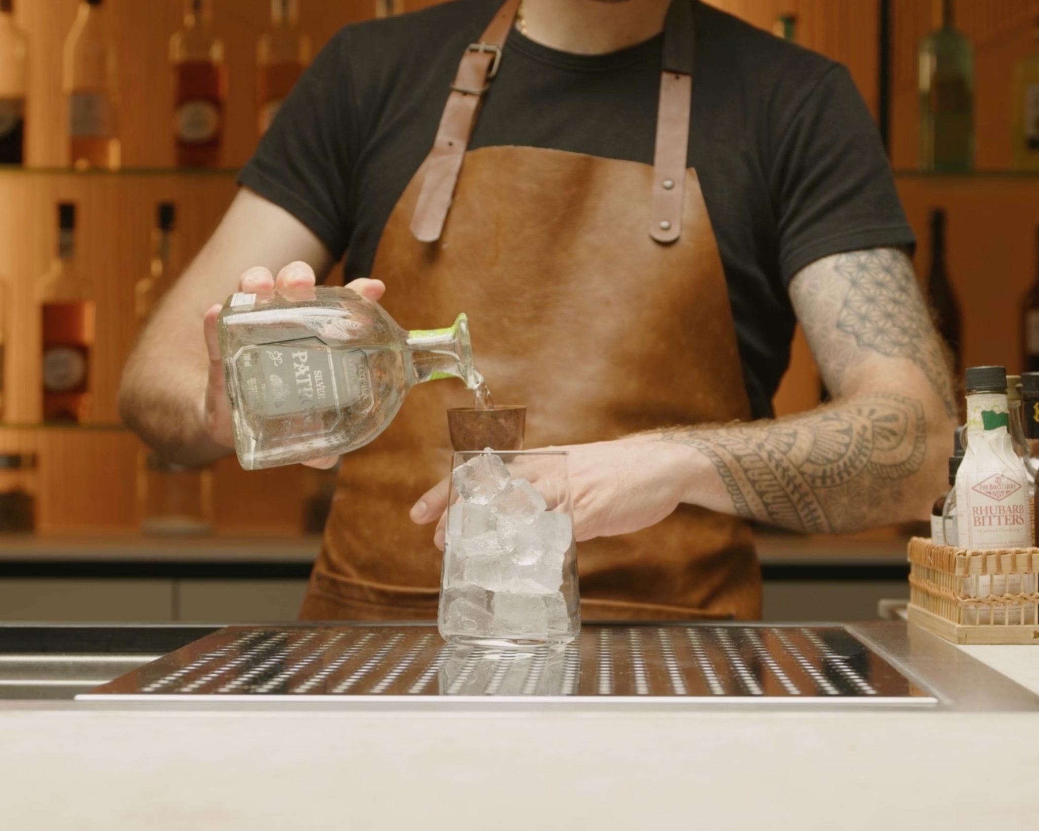 Silver tequila poured into highball glass with jigger