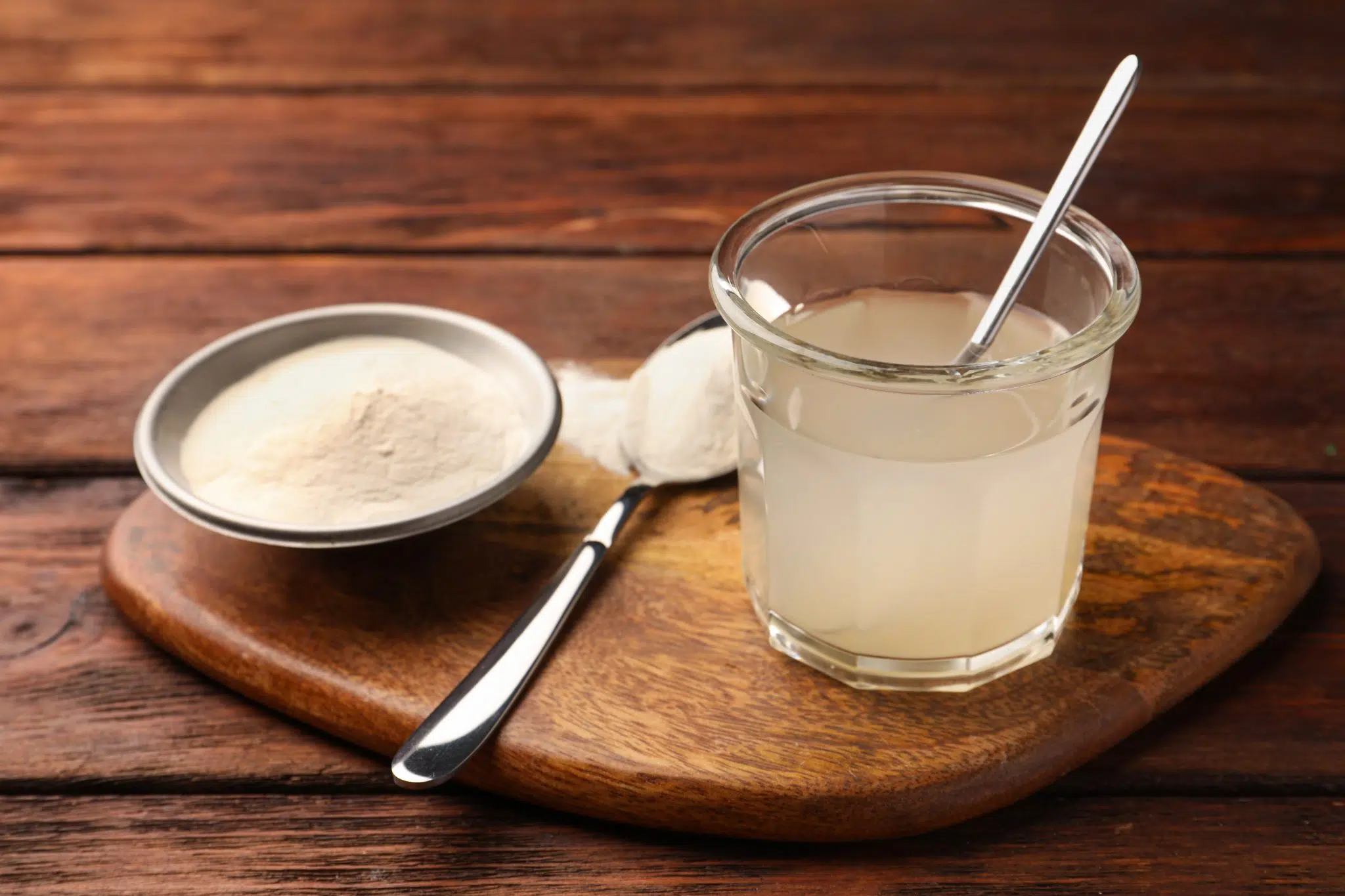 A shot of agar-agar powder in a silver bowl, in a spoon and in a glass mixed with water