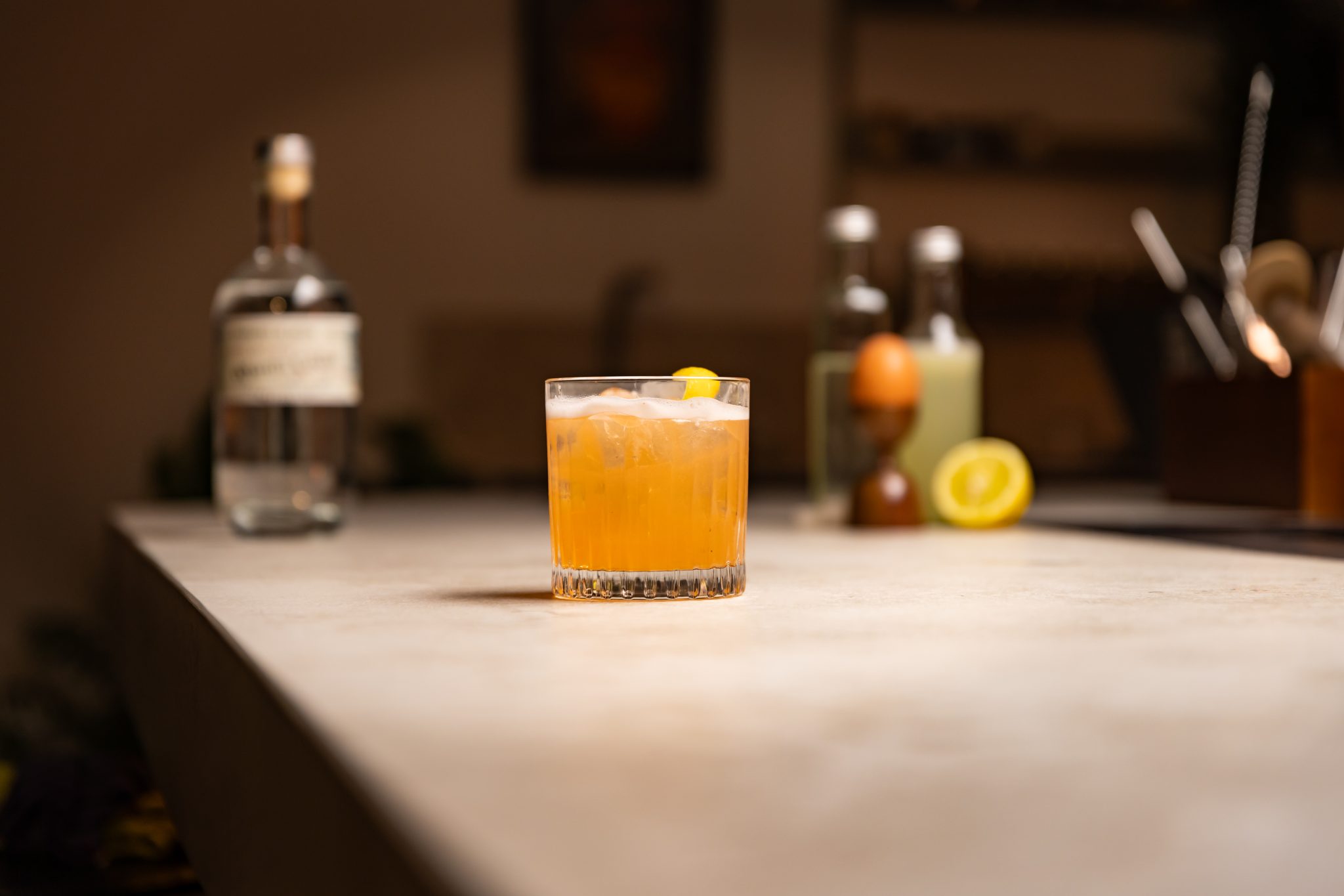 Aguardiente, simple syrup, lemon juice, Angostura bitters, lemon and egg laid out on a white bar table
