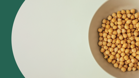 A shot from above of a bowl filled with chickpeas on a white surface