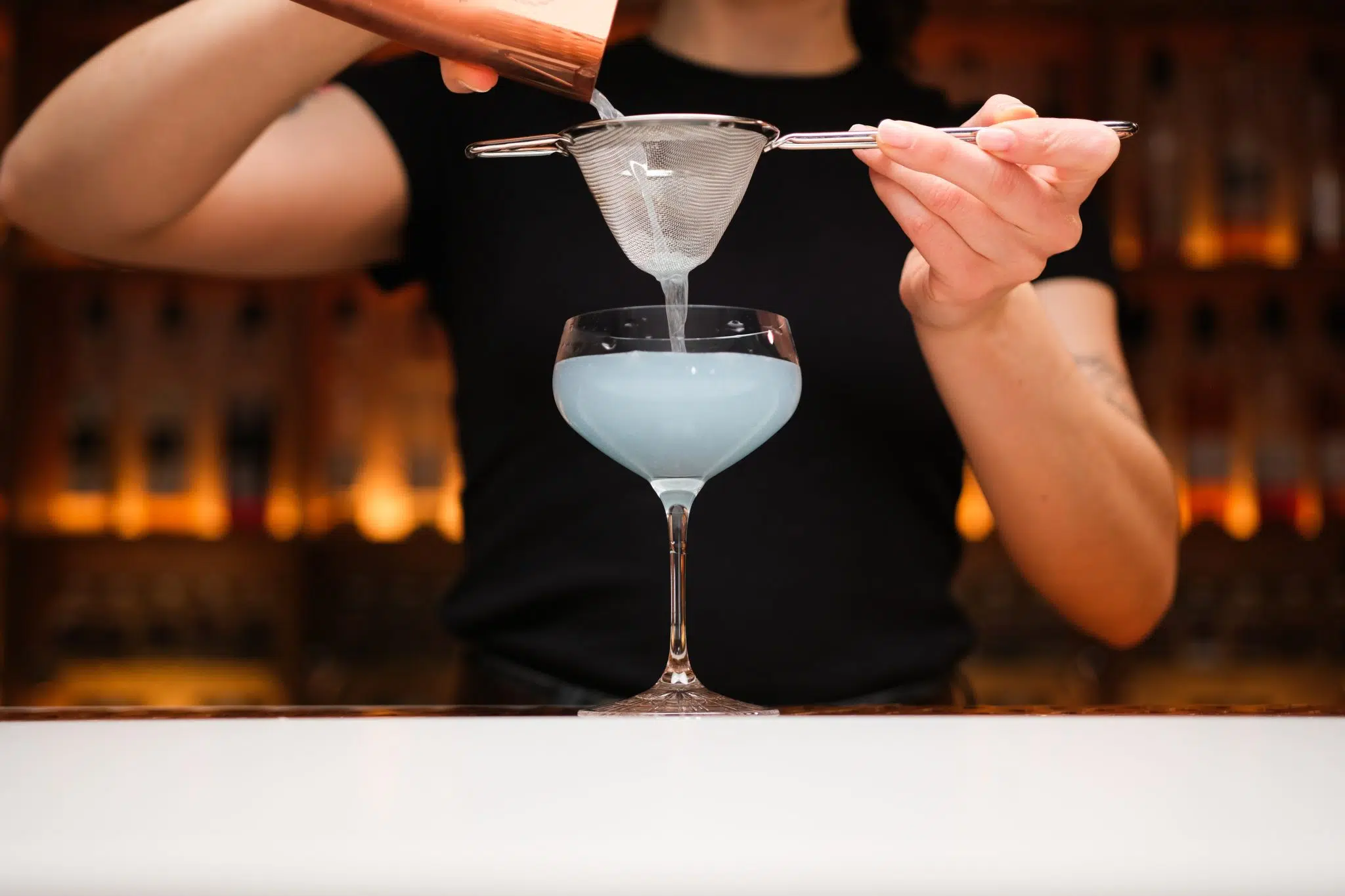 <p>Strain the mixture into your empty and chilled coupe glass. Straining will remove the ice and any pulp, leaving a smooth cocktail in your glass.</p>
