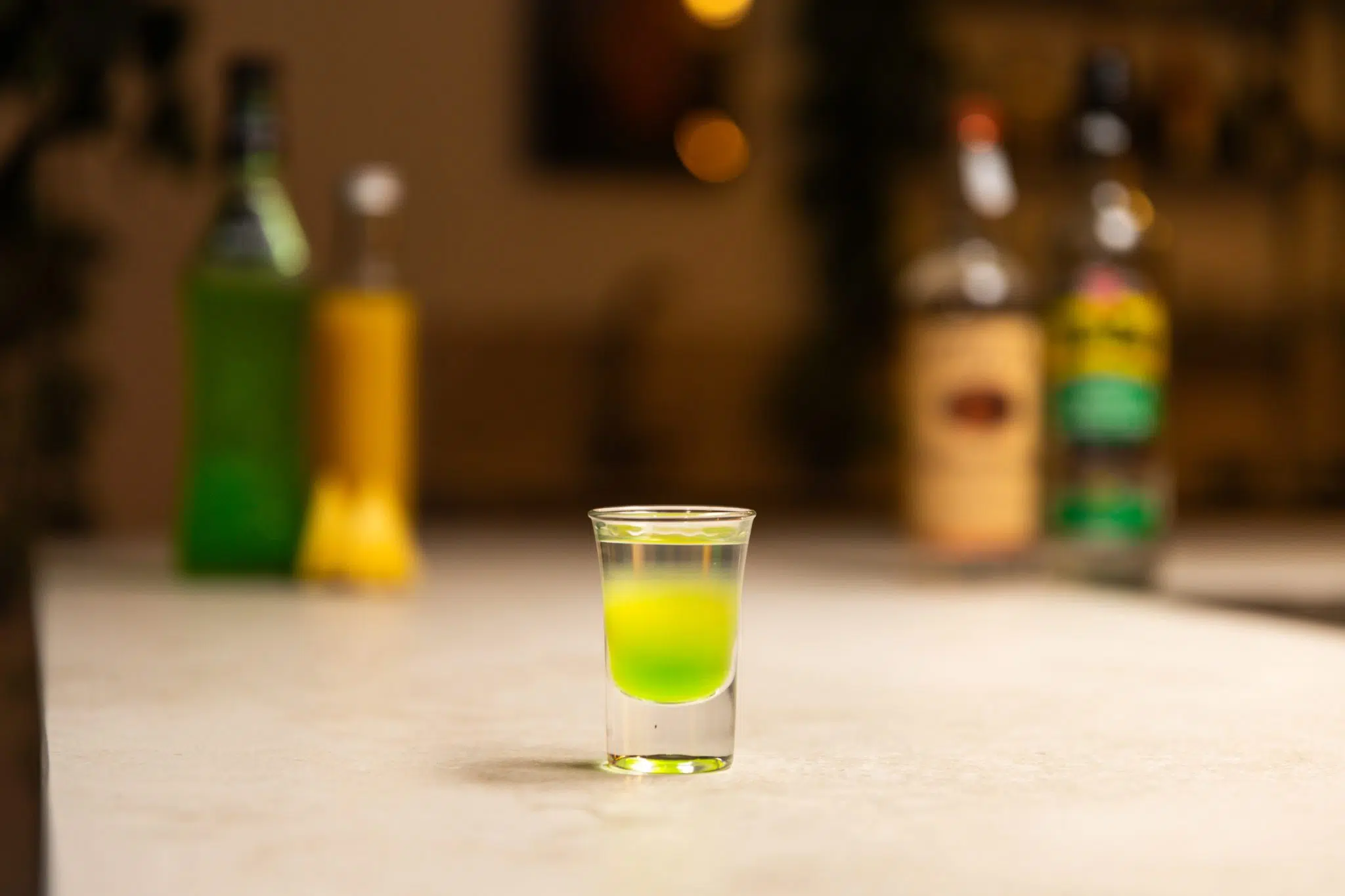 Midori, pineapple juice, pineapple, vodka, and overproof rum laid out on a white bar table