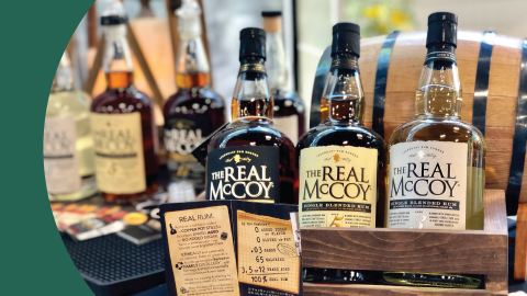 A shot of different aged rum bottles with a barrel behind