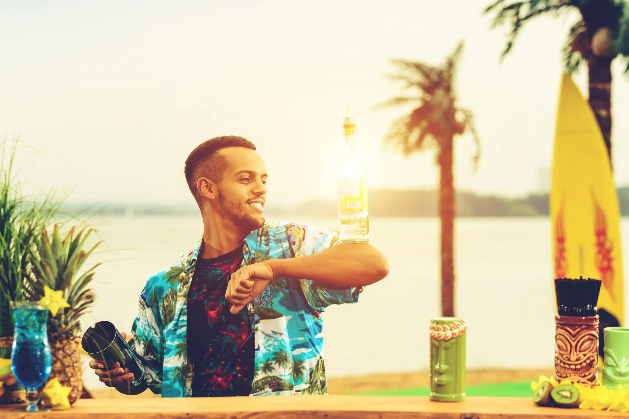 A shot of a bartender working for a private tropical event and holding a bottle on the elbow