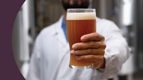 A shot of a Cicerone with a white shirt holding a pint glass filled with beer