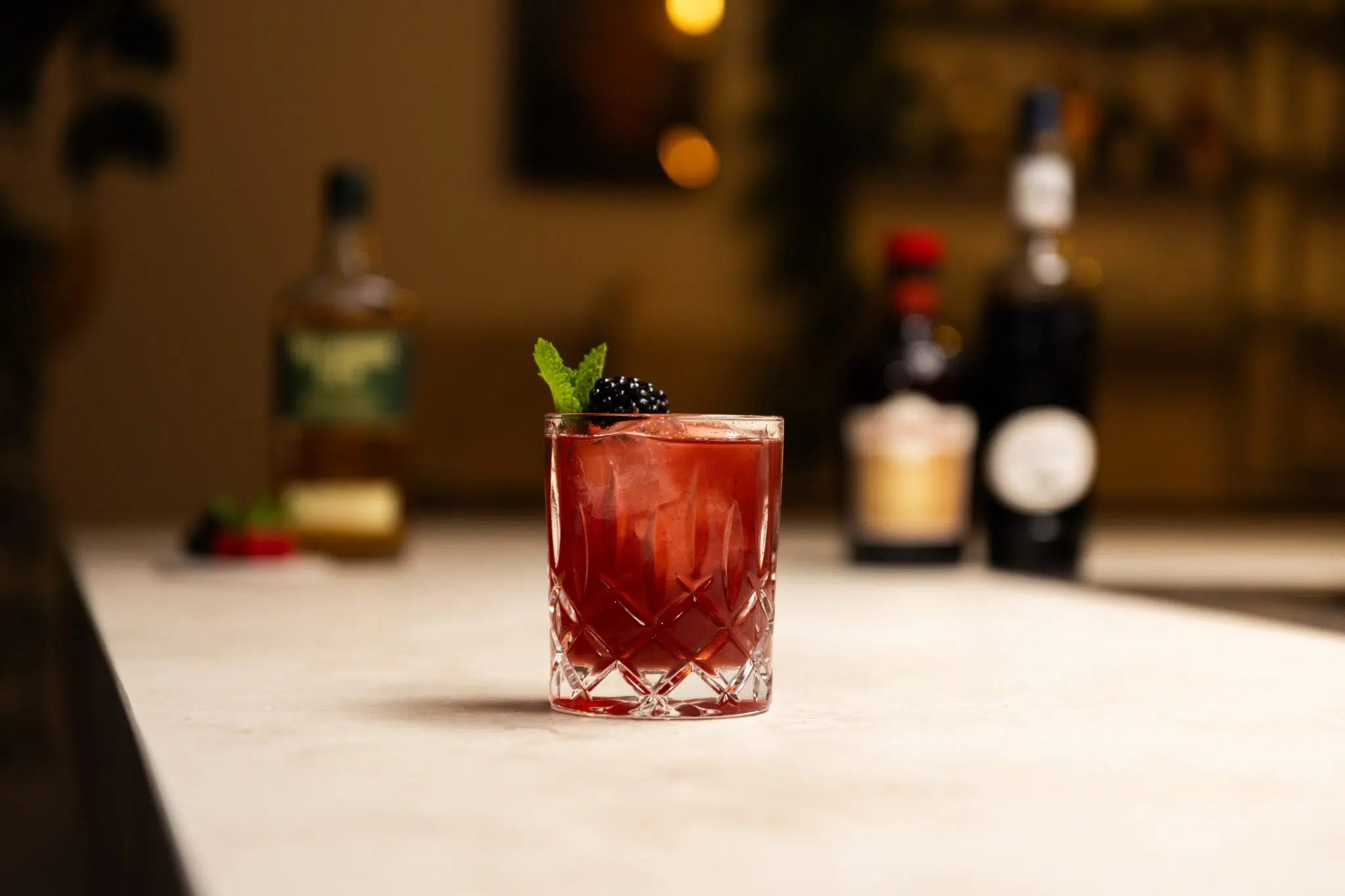 Irish Whiskey, Drambuie, Creme de Cassis, raspberries and blackberries laid out on a white bar table