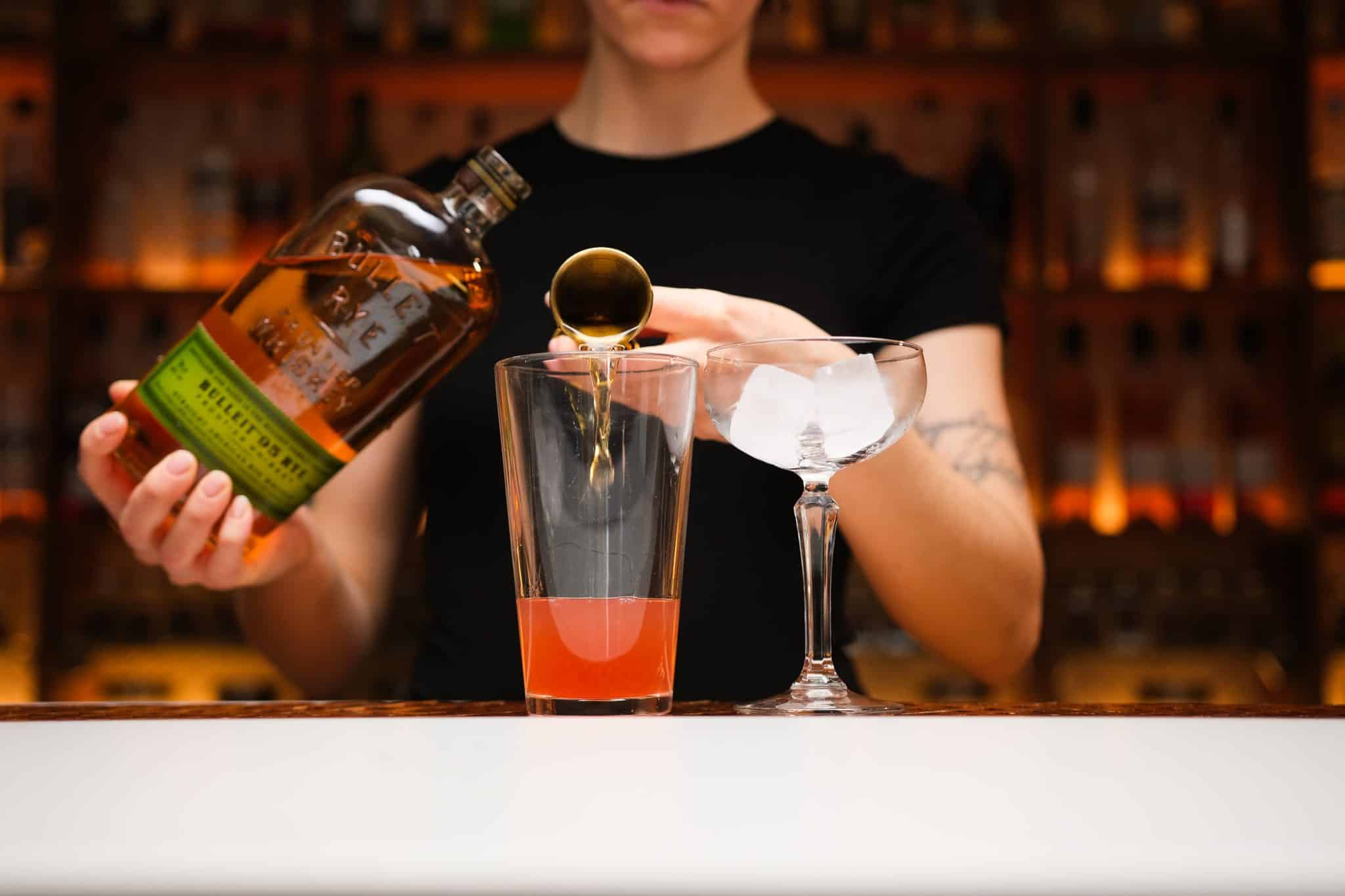 <p>Pour rye whiskey into the shaker, setting the stage for the drink’s bold character.</p>
