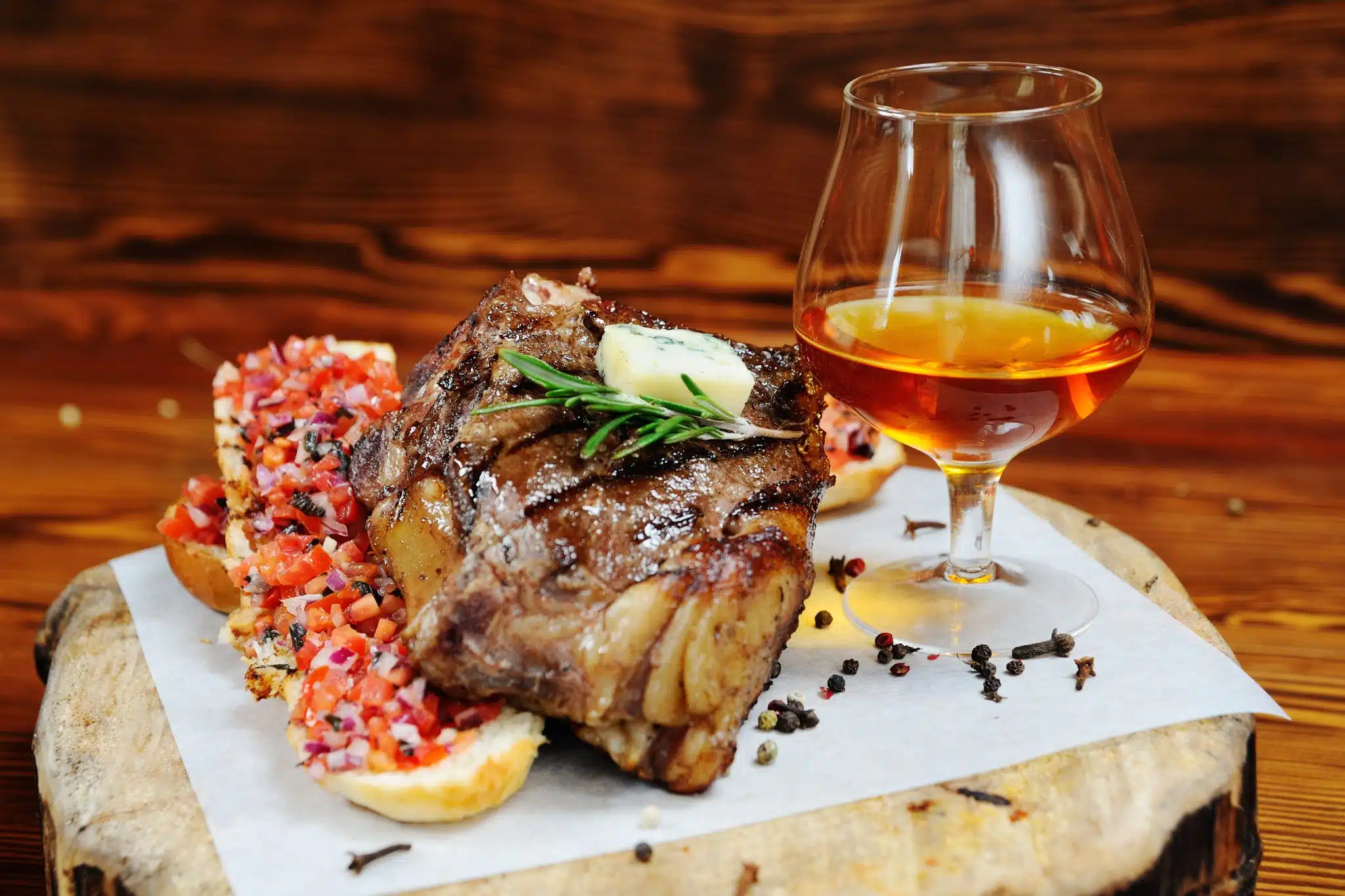Grilled pork chop on a wooden board with brandy and bruschetta.