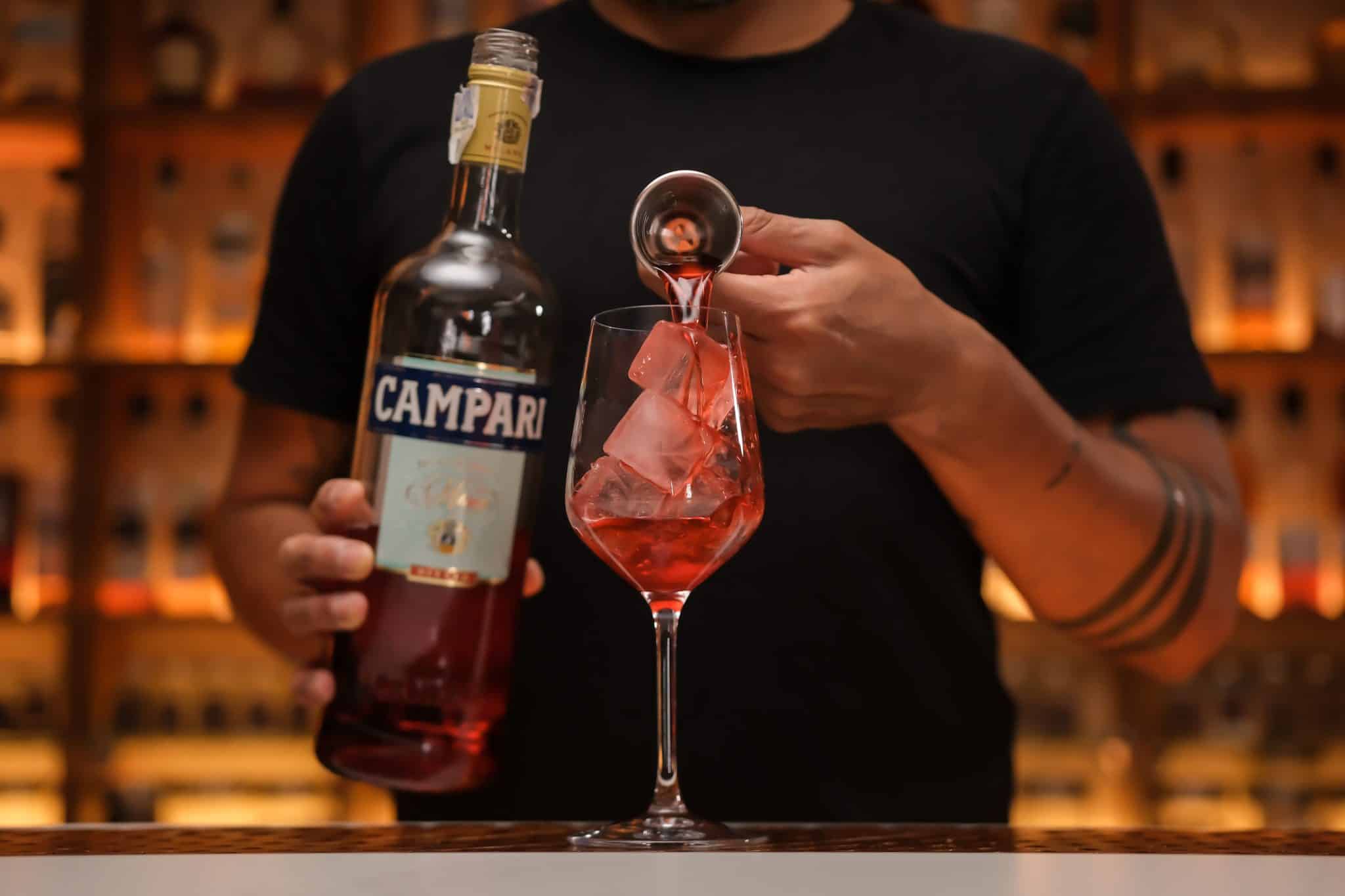 <p>Measure and pour 2 oz of Campari into the glass, introducing a bold bitterness and a vibrant red color.</p>

