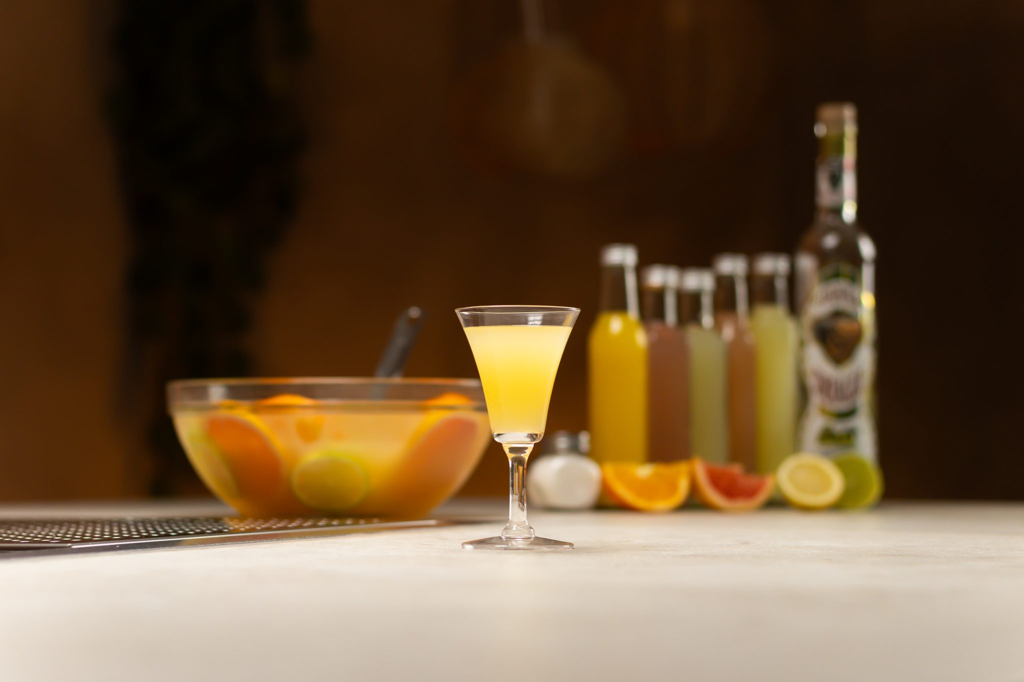 Tequila, orange juice, grapefruit juice, lemon juice, lime juice, grapefruit soda, fine sea salt, punch with cazuela drink, lime, lemon and orange laid out on a white bar table