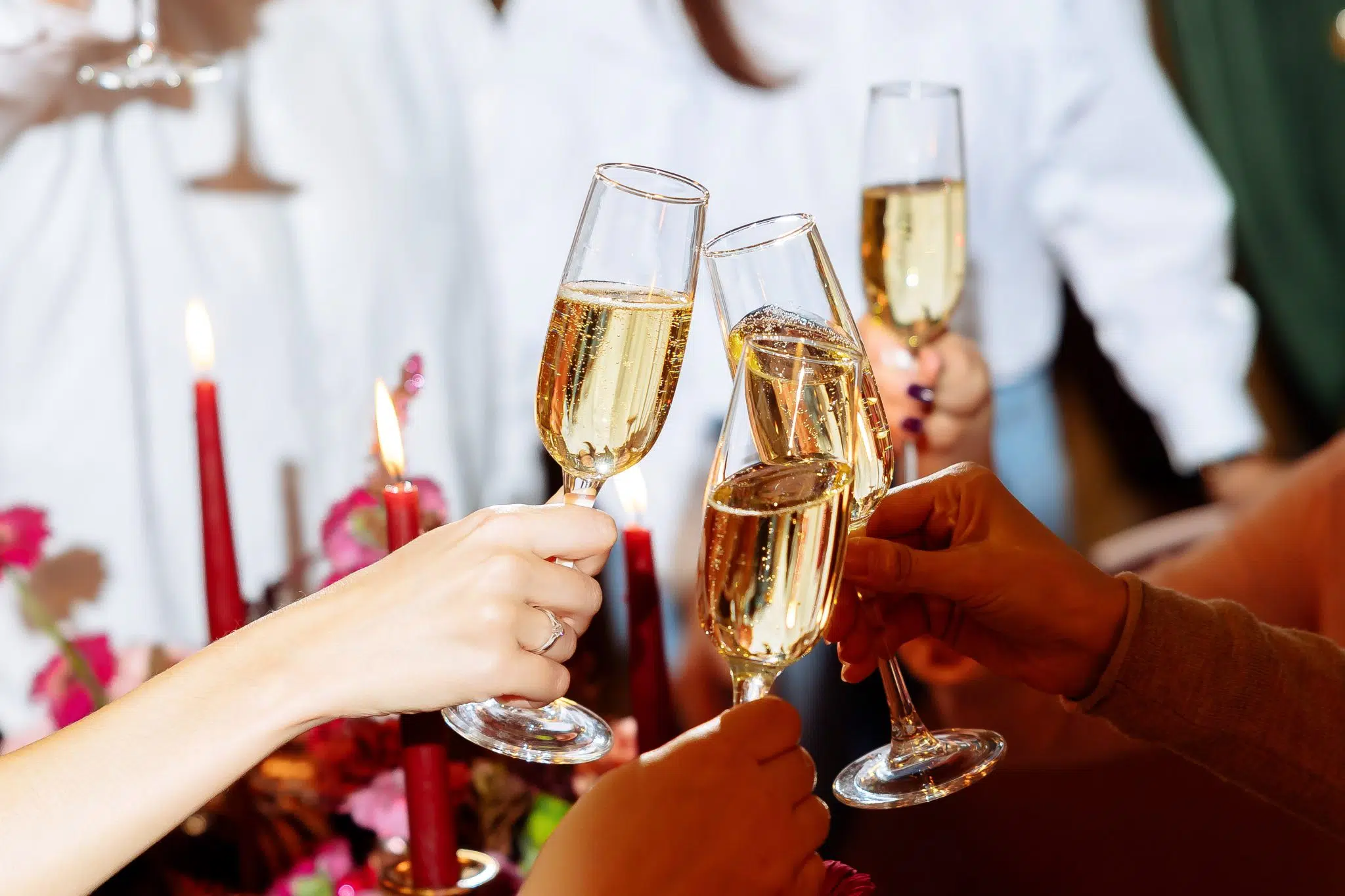 A shot of many hands toasting with champagne flutes holded by the stem