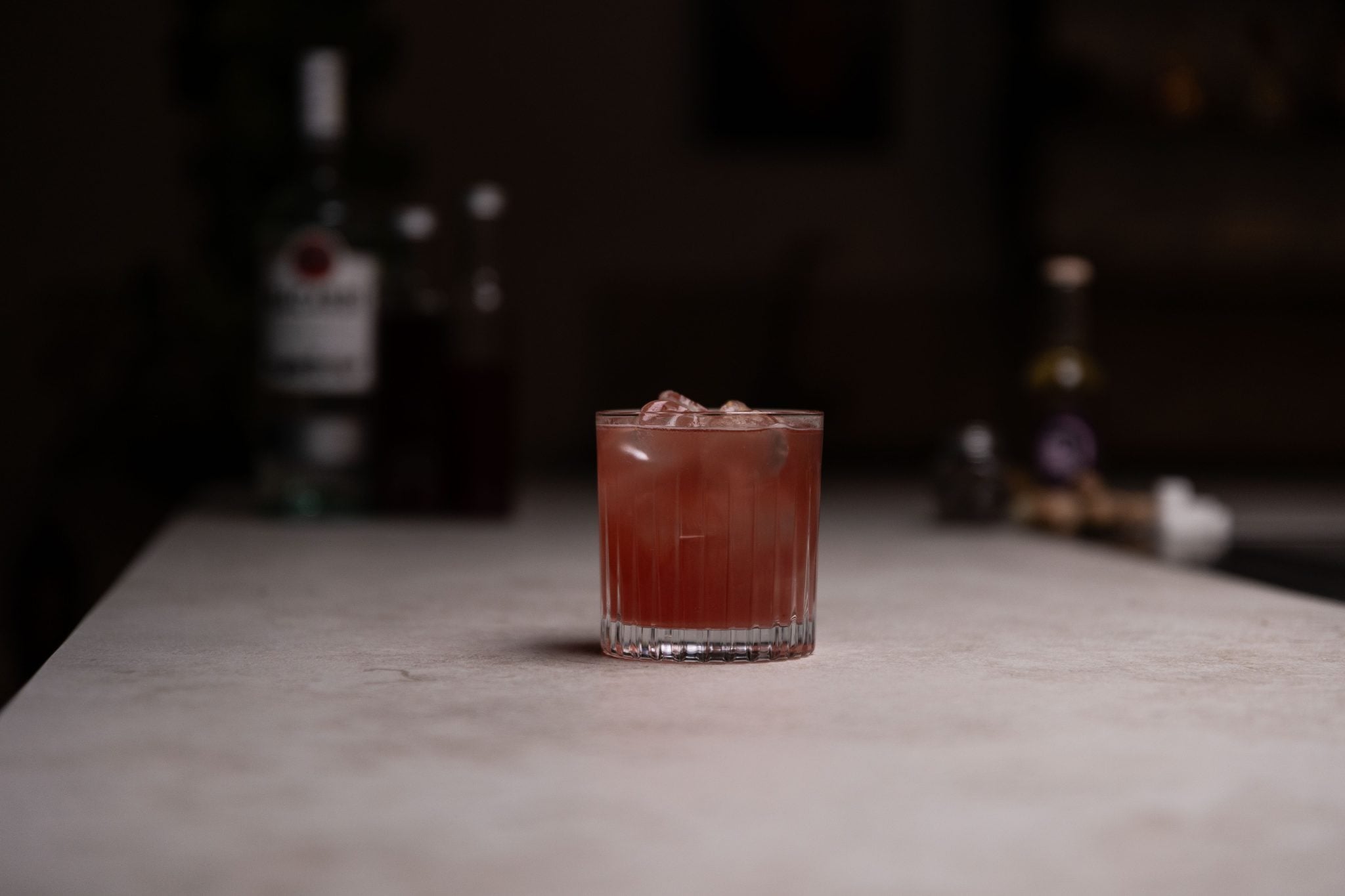 Light rum, cranberry juice, tart cherry juice, rich simple syrup, sugar cubes, allspice, ginger, nutmeg and ginger ale laid out on a white bar table