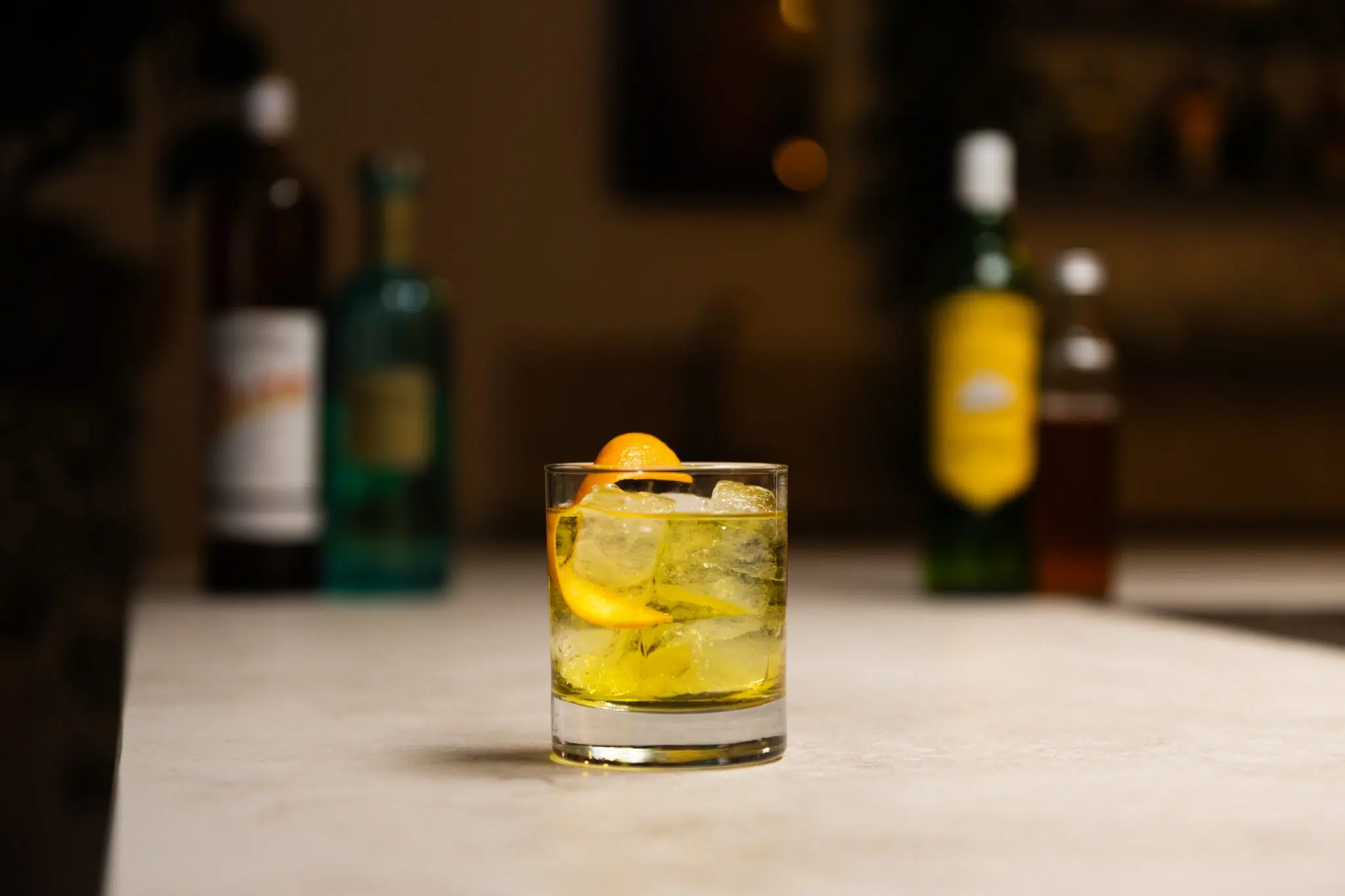 Honey syrup, Italicus, Gentian liqueur, and blended scotch whisky laid out on a white bar table