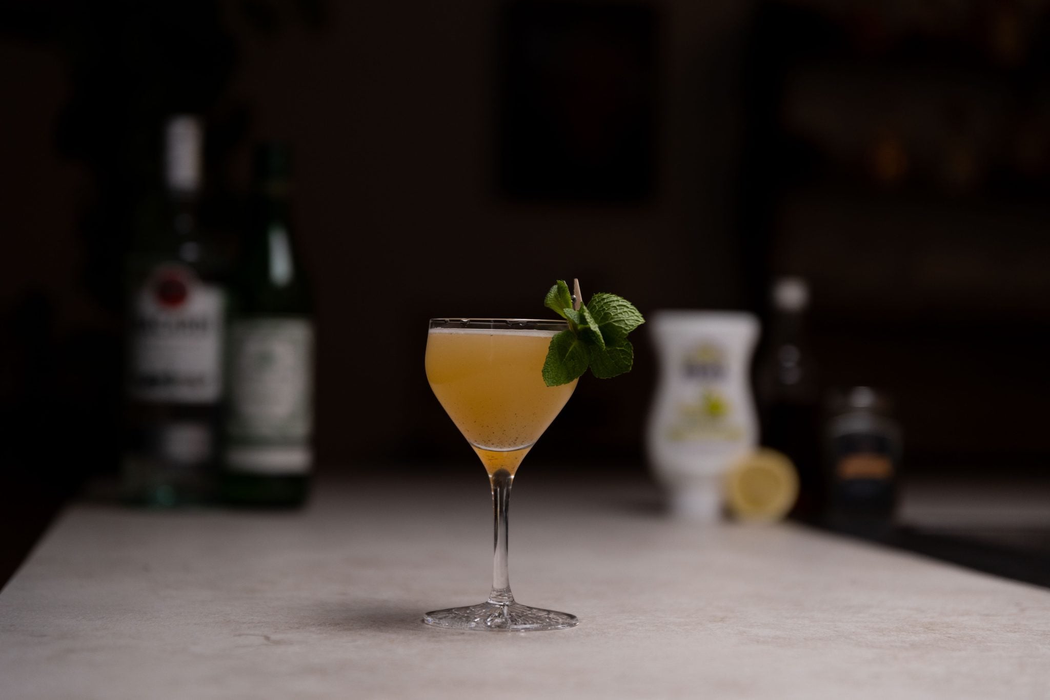 White rum, dry vermouth, pear puree, honey syrup, black peppercorns, lemon juice and lemon laid out on a white bar table