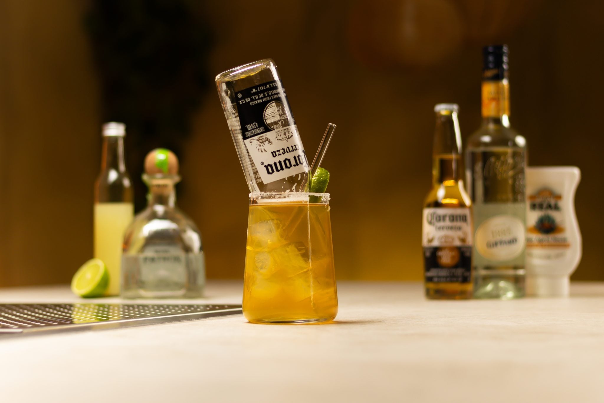 Tequila, lime juice, Triple Sec agave syrup, Corona beer and lime laid out on a white bar table