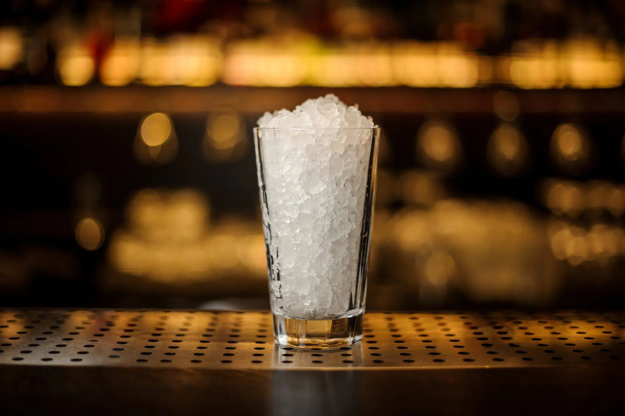 Crushed ice in a highball glass on a bar table