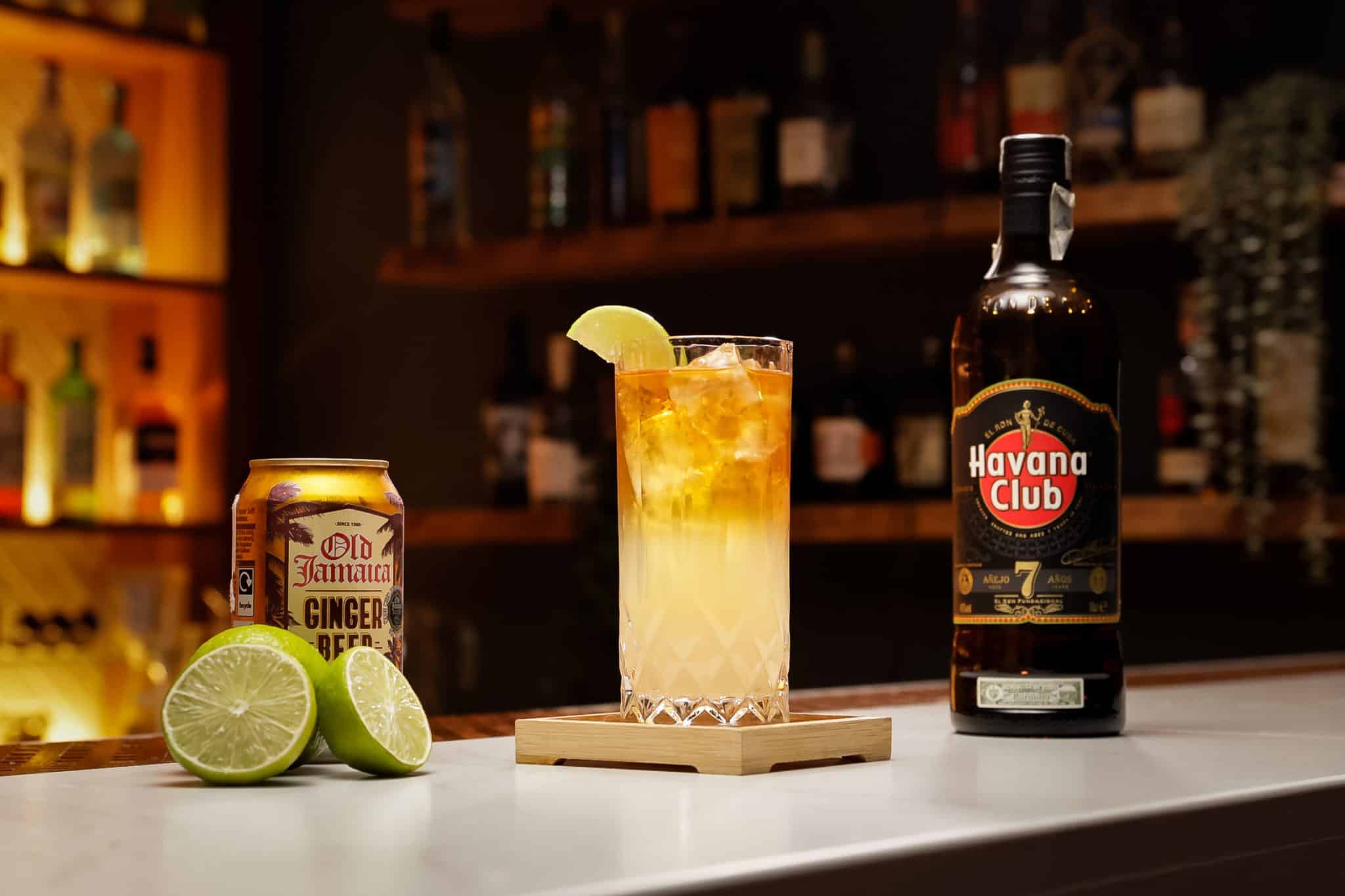 Dark rum, ginger beer and lime juice laid out on a white bar table