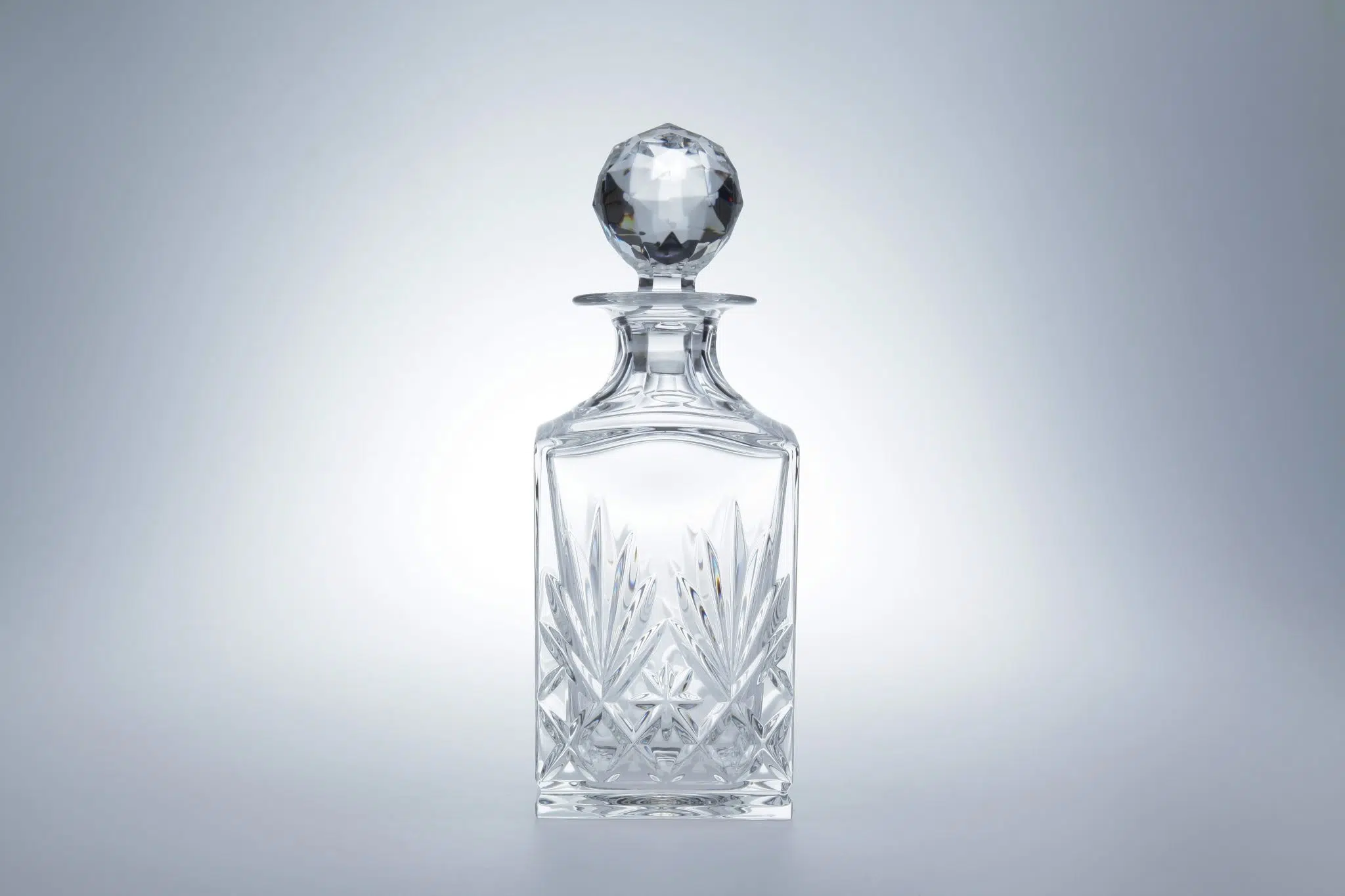 A crystal decanter on a gray background