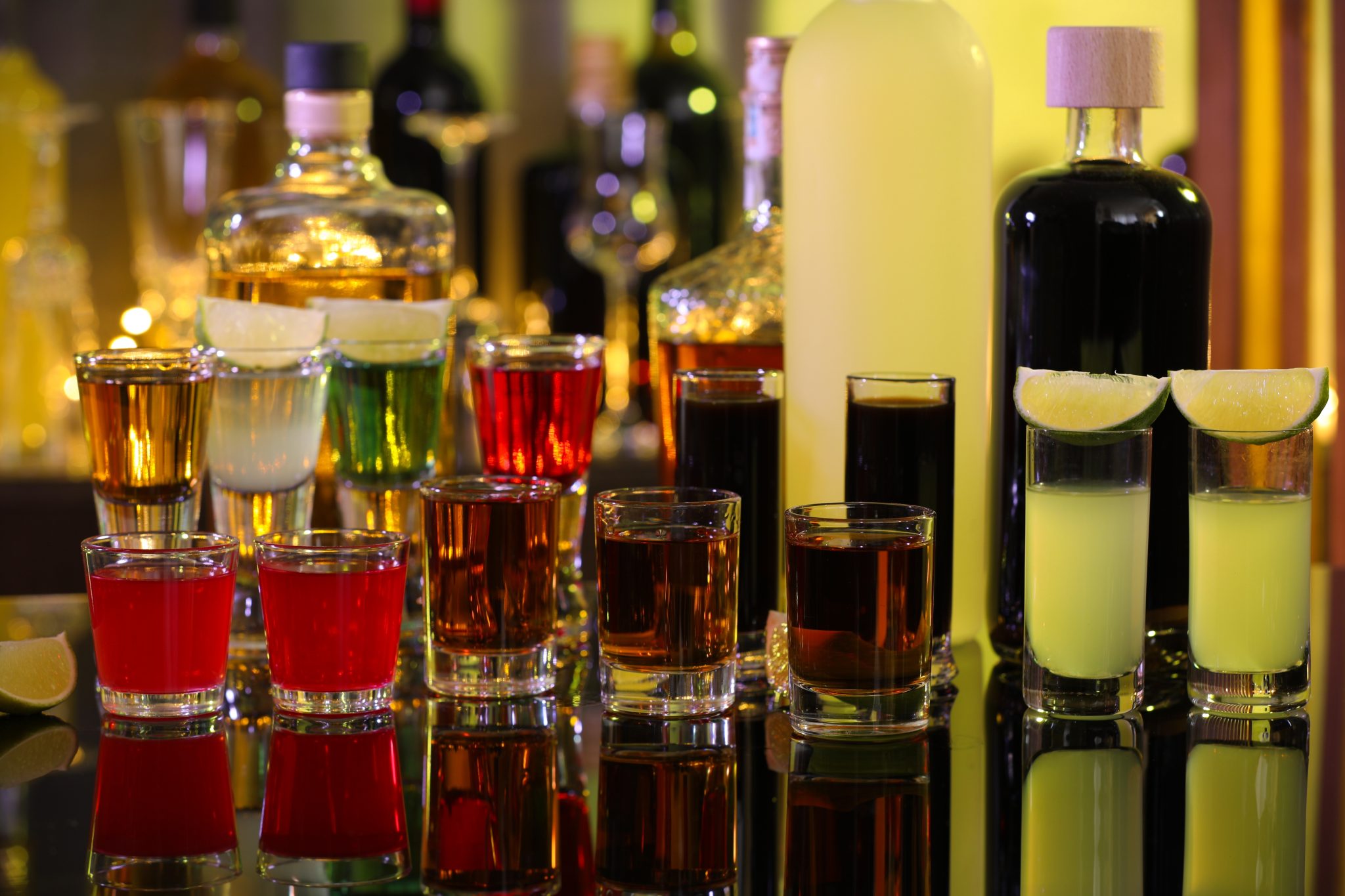 A shot of different shooters in shot glasses and bottles on the background