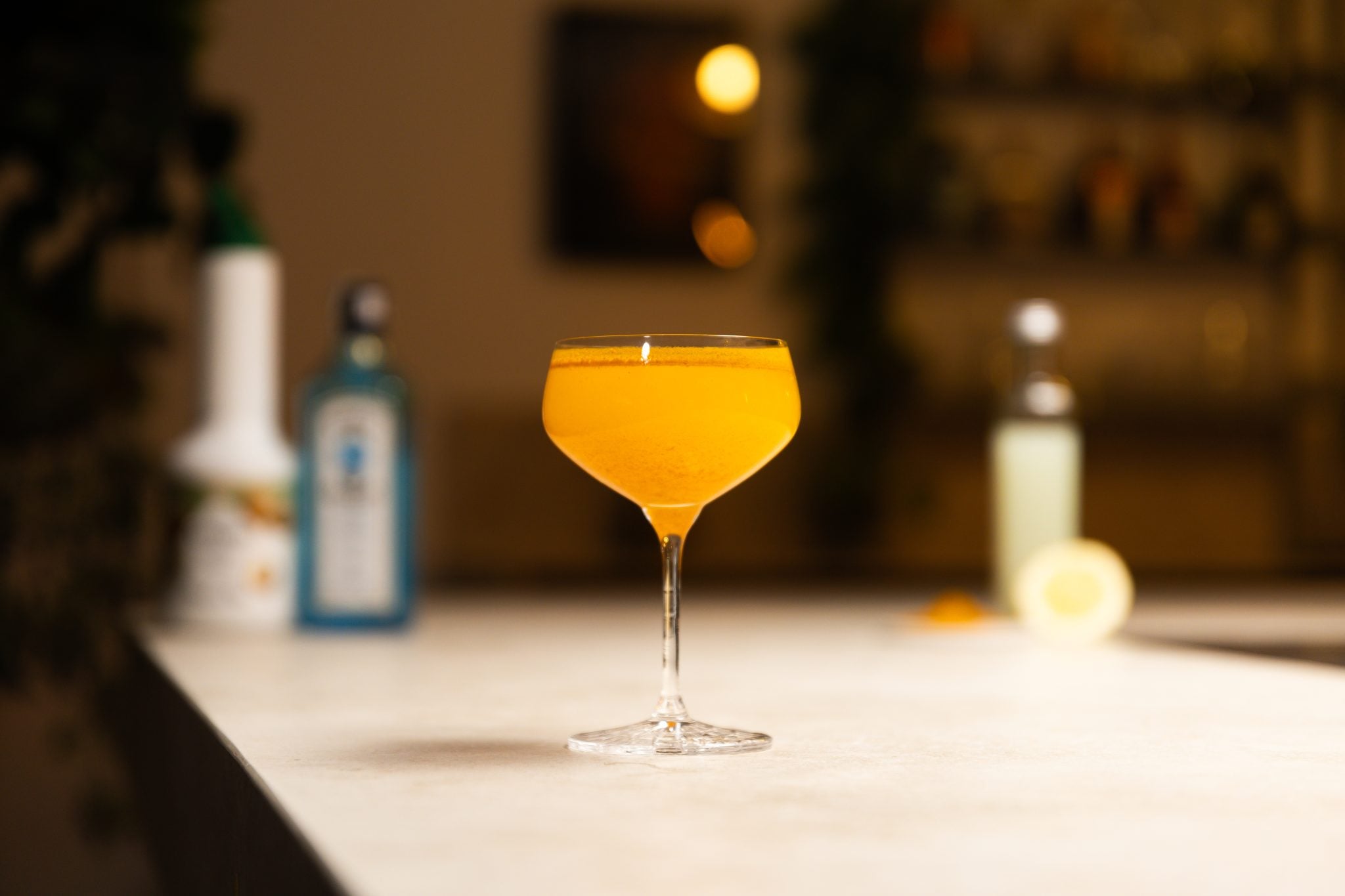 London Dry Gin, cream of coconut, lemon juice, lemon and curry powder laid out on a white bar table