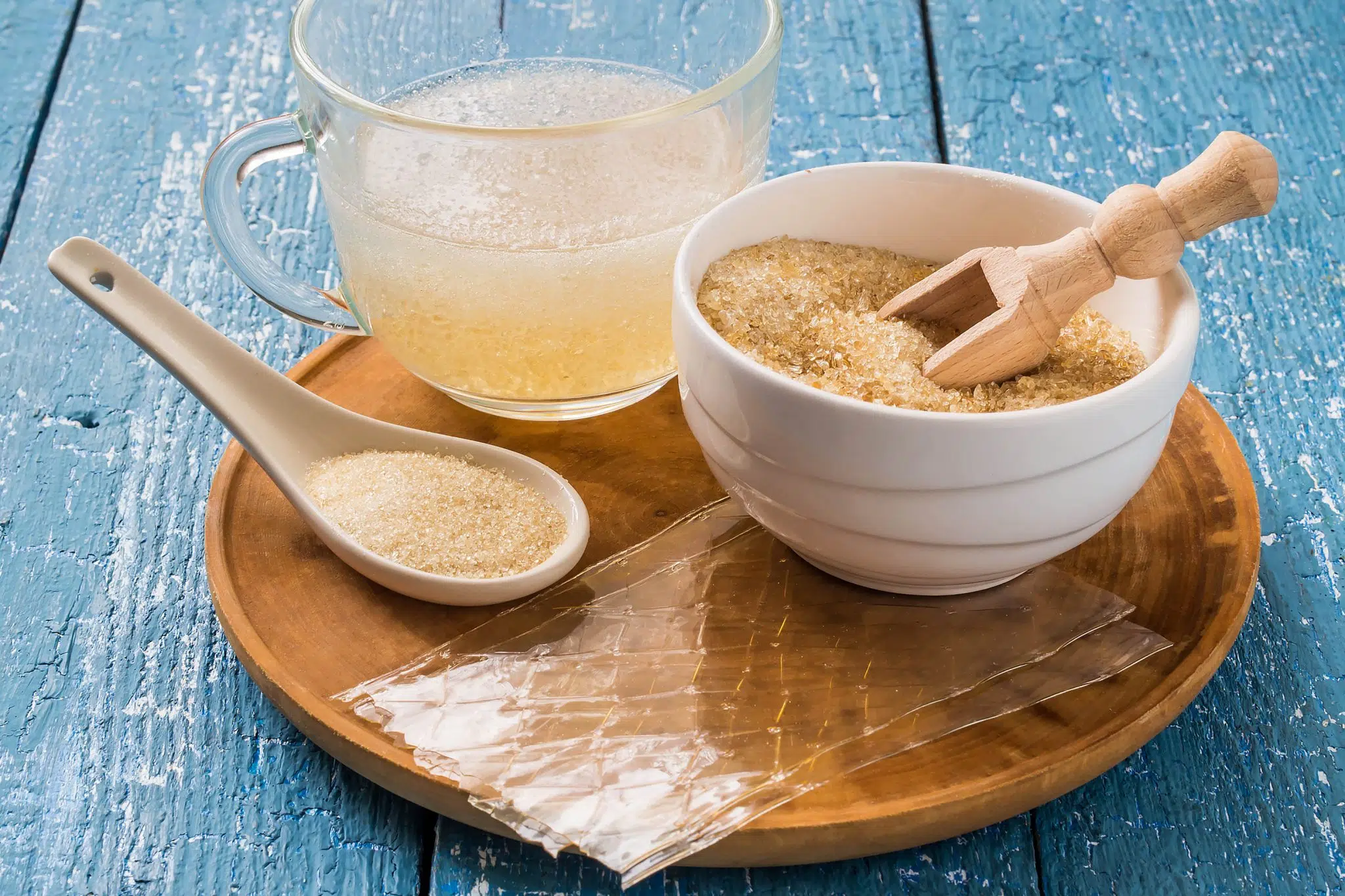 A shot of a gelatin powder, granulated gelatin on a spoon, gelatin sheets and gelatin mixed with water on a big transparent bowl