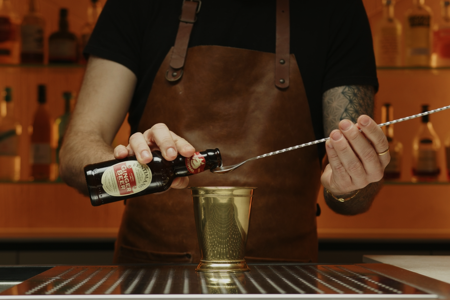 <p>Measure and pour a bar spoon of ginger beer onto the sugar cube. The ginger beer not only helps to dissolve the sugar but also starts to infuse the drink with its spicy flavor.</p>