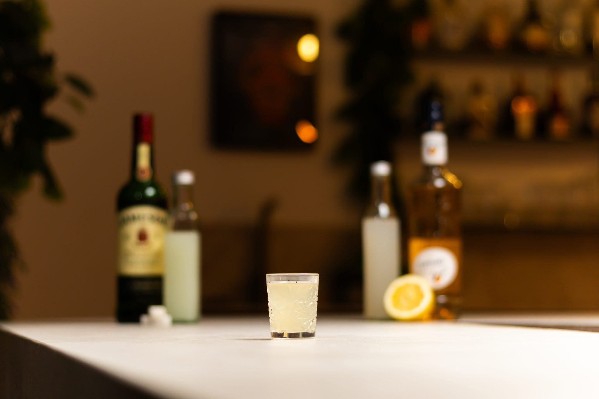 Jameson Irish Whiskey, Peach Schnapps, sour mix, and lemon-lime soda laid out on a white bar table
