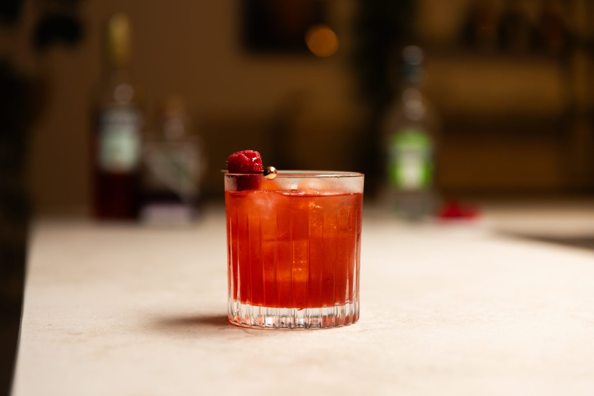 London Dry Gin, Sloe Gin, Campari, raspberries in a plate laid out on a white bar table