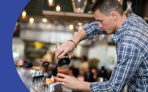 A shot of a bartender closing a cocktail shaker behind a bar table