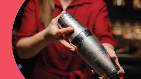 A shot of a woman in red clothes holding a boston cocktail shaker