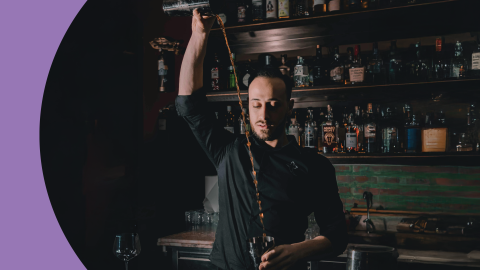 A shot of a bartender rolling a cocktail in a bar