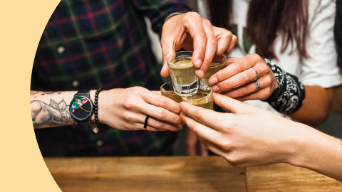 A shot of the hands of a group of people toasting with tequila shots