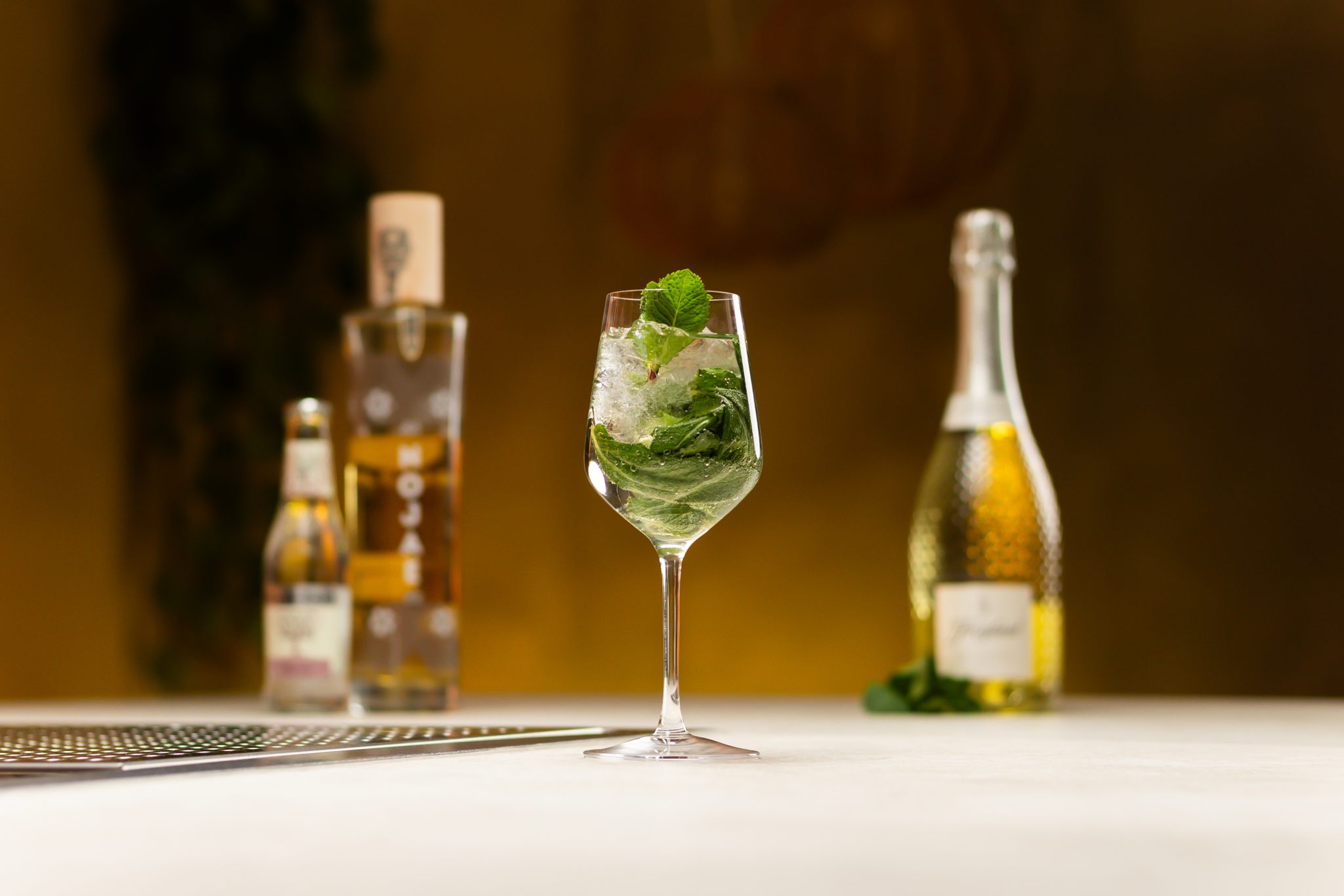 Saint Germain elderflower liqueur, Prosecco, soda water and mint leaves laid out on a white bar table