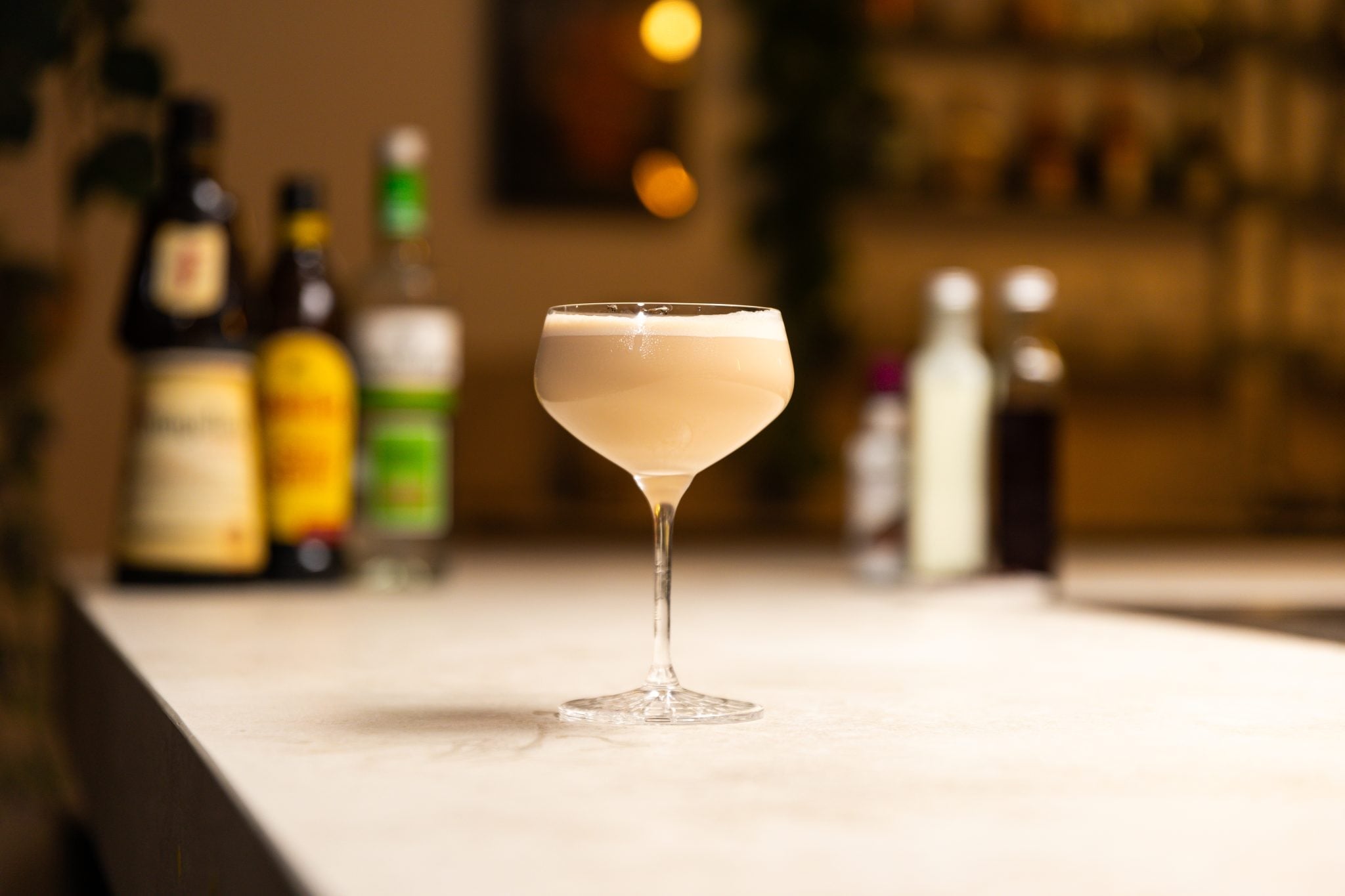 Vodka, coffee liqueur, hazelnut liqueur, brewed espresso, chocolate bitters, single cream, and coffee beans laid out on a white bar table
