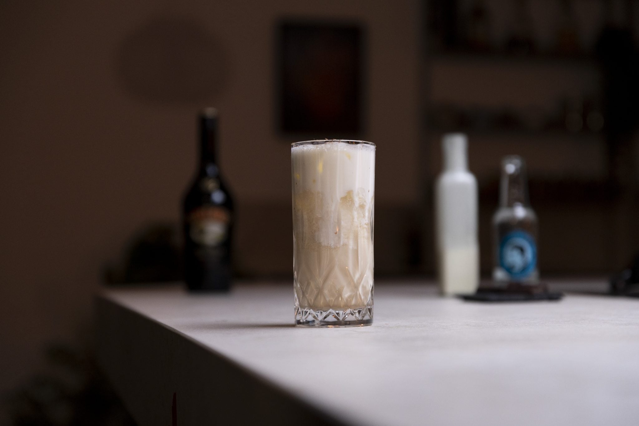 Irish cream liqueur, soda water, cream, and chocolate squares laid out on a white bar table