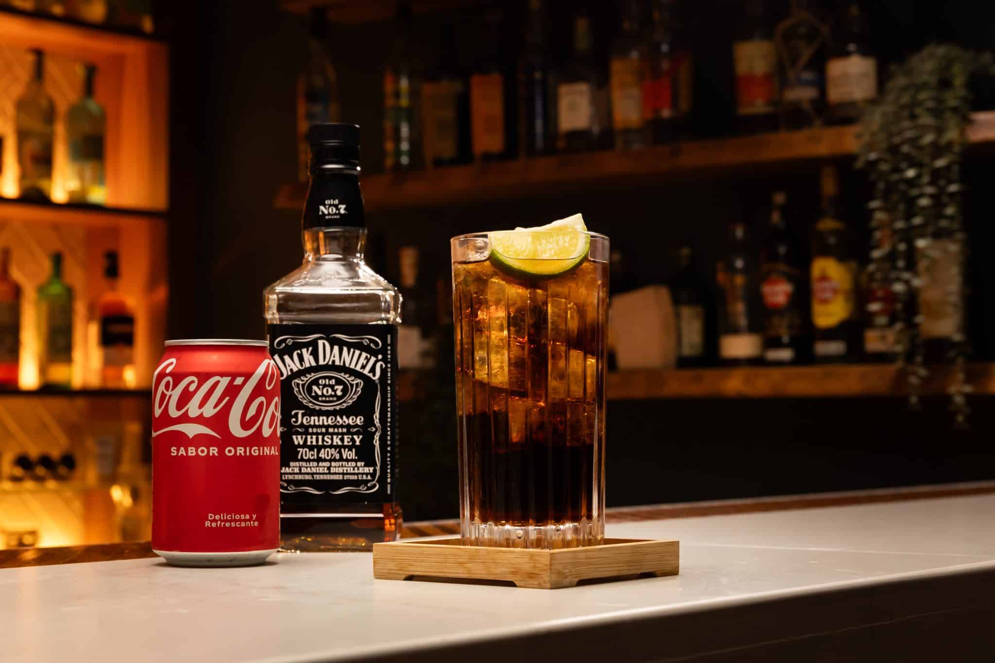 Whiskey and cola laid out on a white bar table