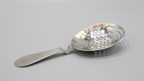 A shot of a Julep strainer on a grey background