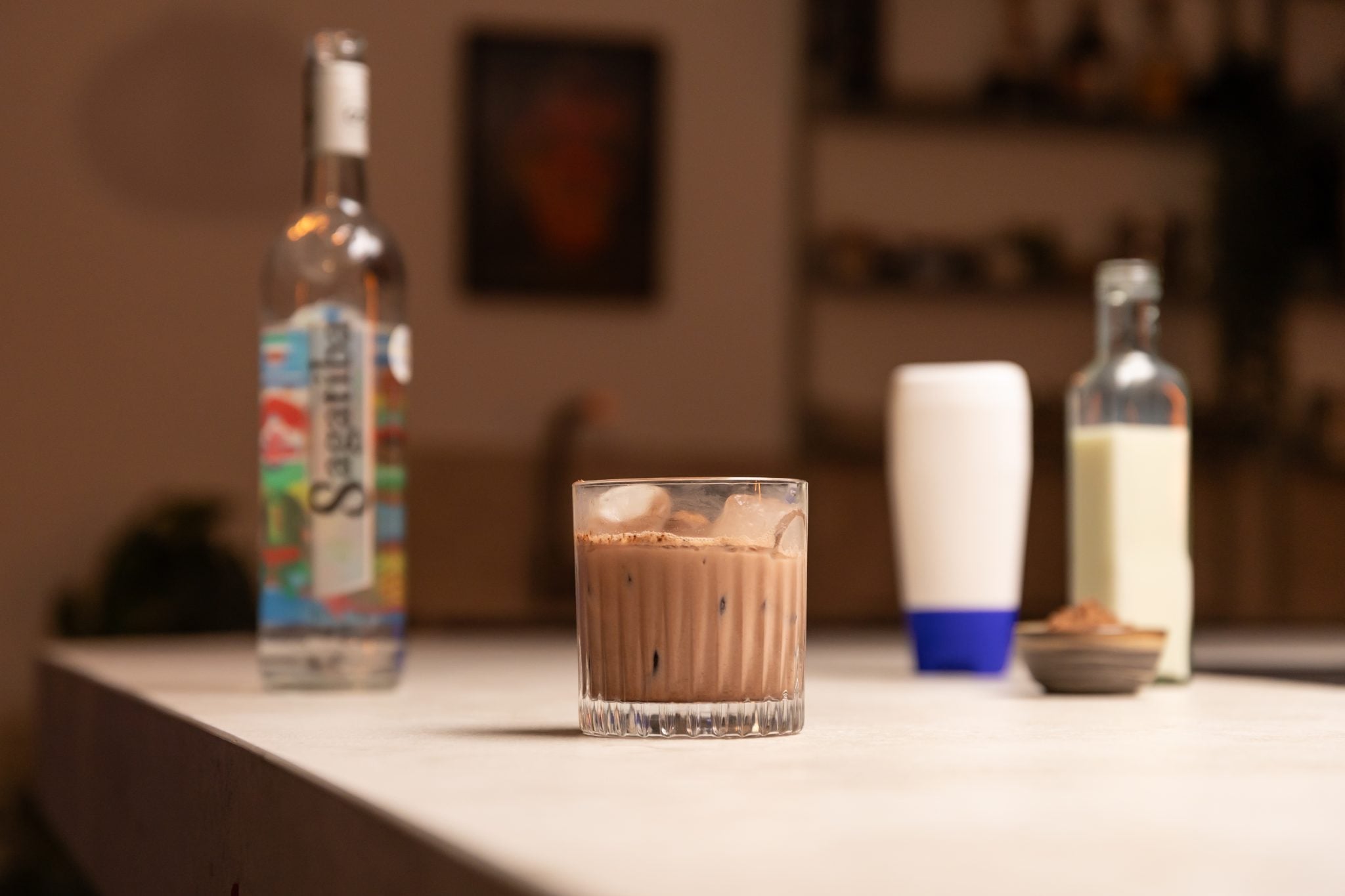 Cachaça, condensed milk, milk, and cocoa powder laid out on a white bar table