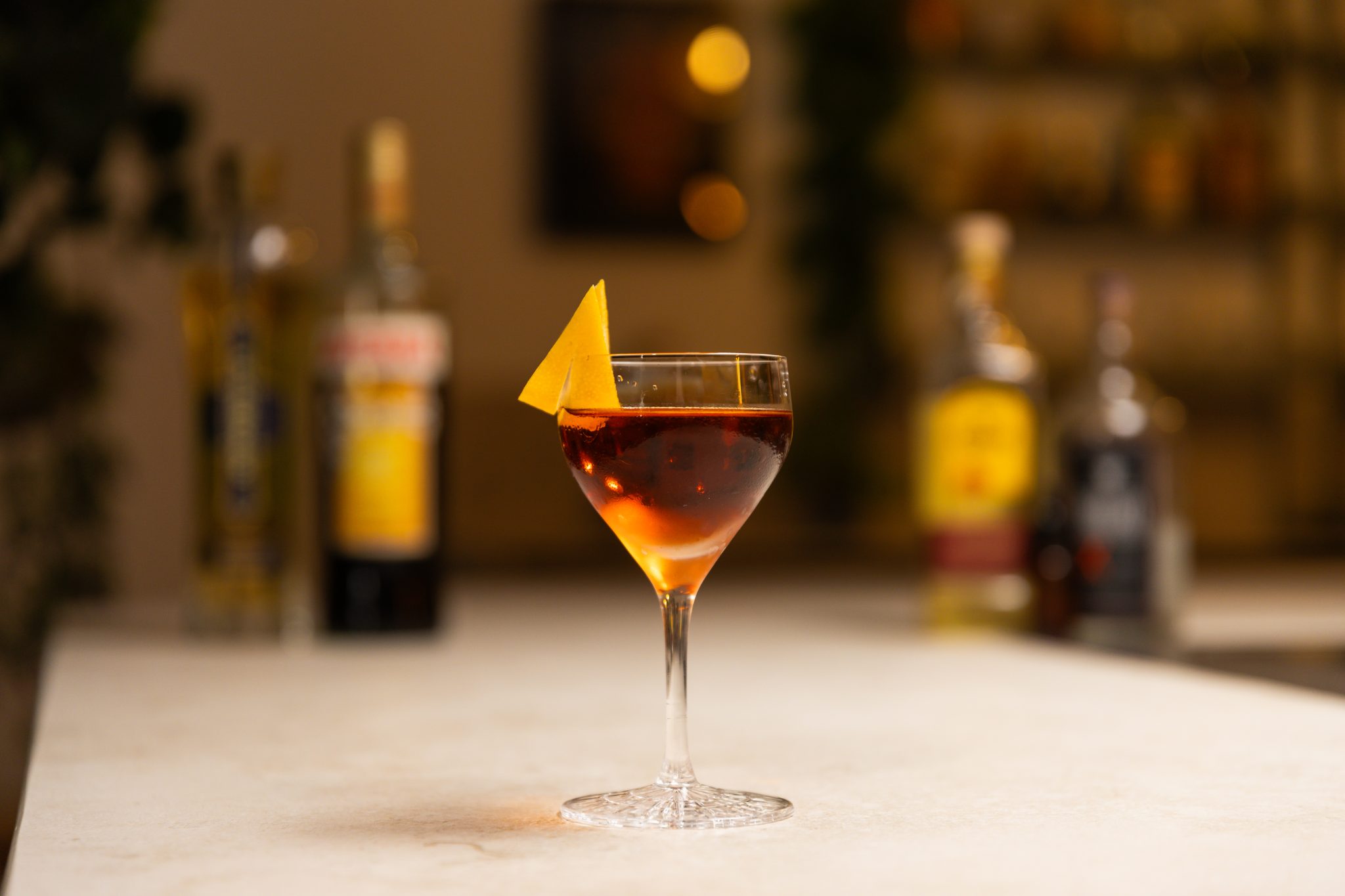 Tequila Añejo, Mezcal, Amaro Averna, elderflower liqueur and grapefruit bitters laid out on a white bar table