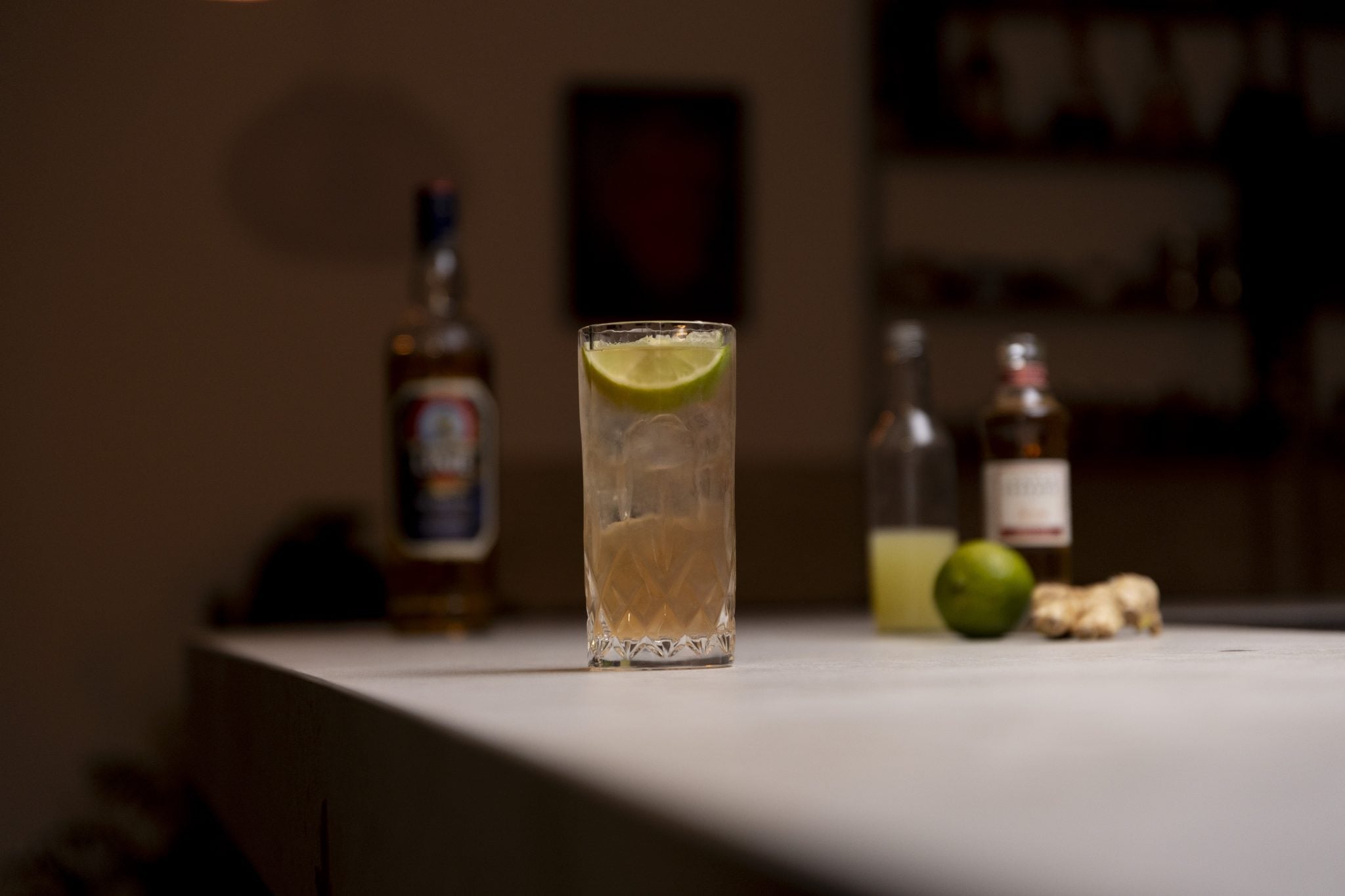 Aquavit, ginger beer, lime juice, lime and ginger laid out on a white bar table