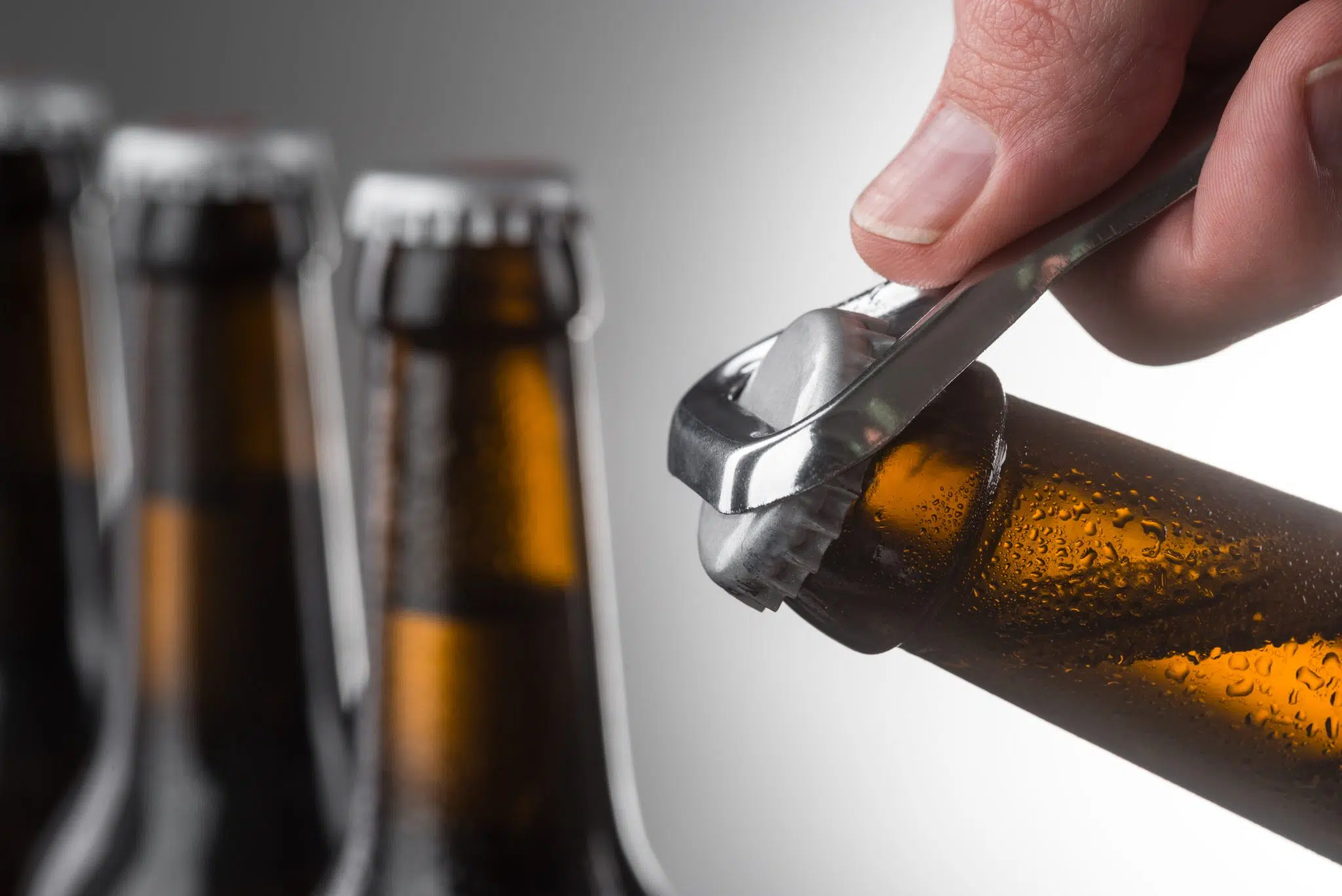 Opening bottle of beer using a metal opener