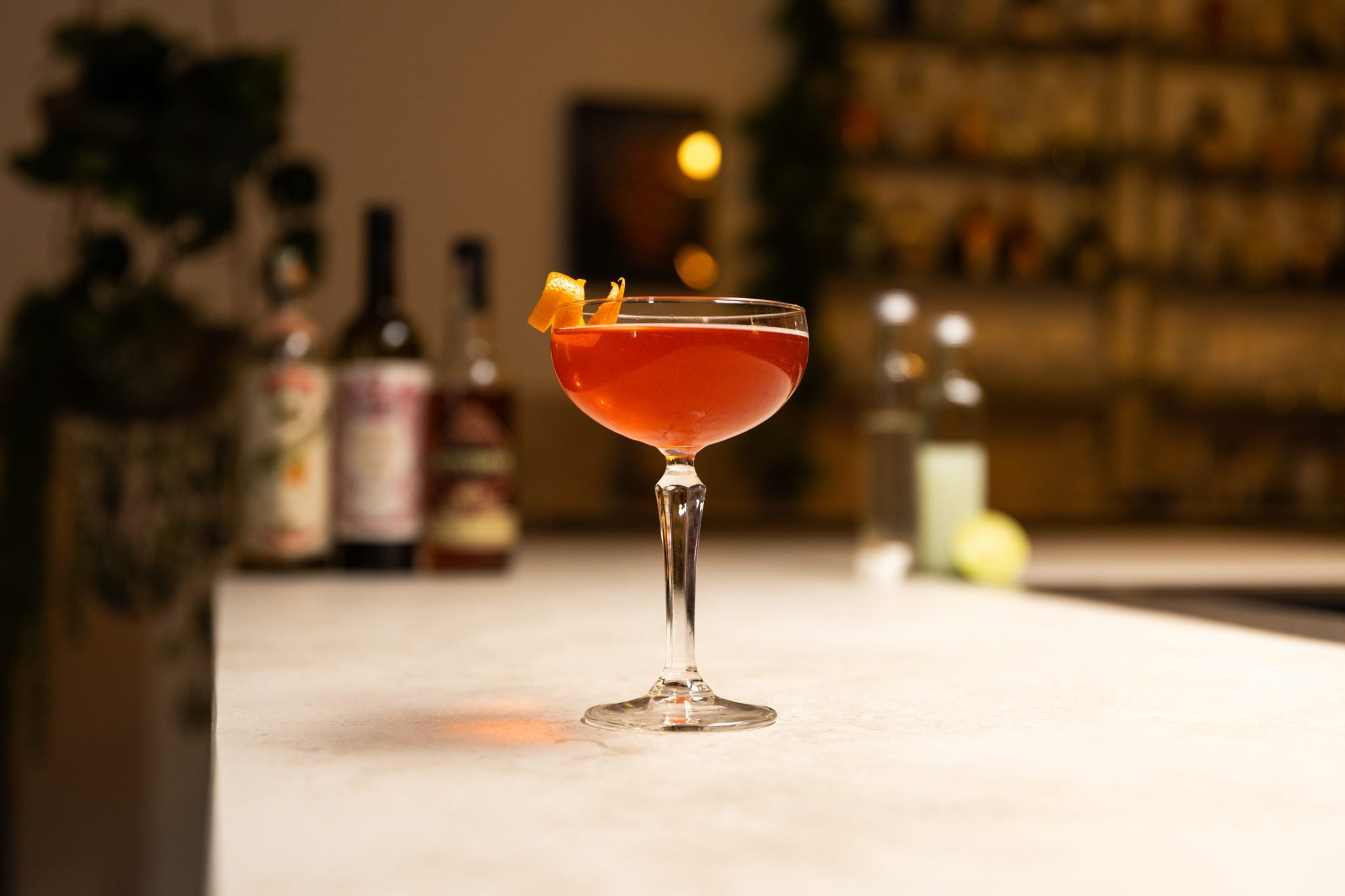 Rye whiskey, curaçao, sweet vermouth, lime juice, lime, sugar cubes and simple syrup laid out on a white bar table