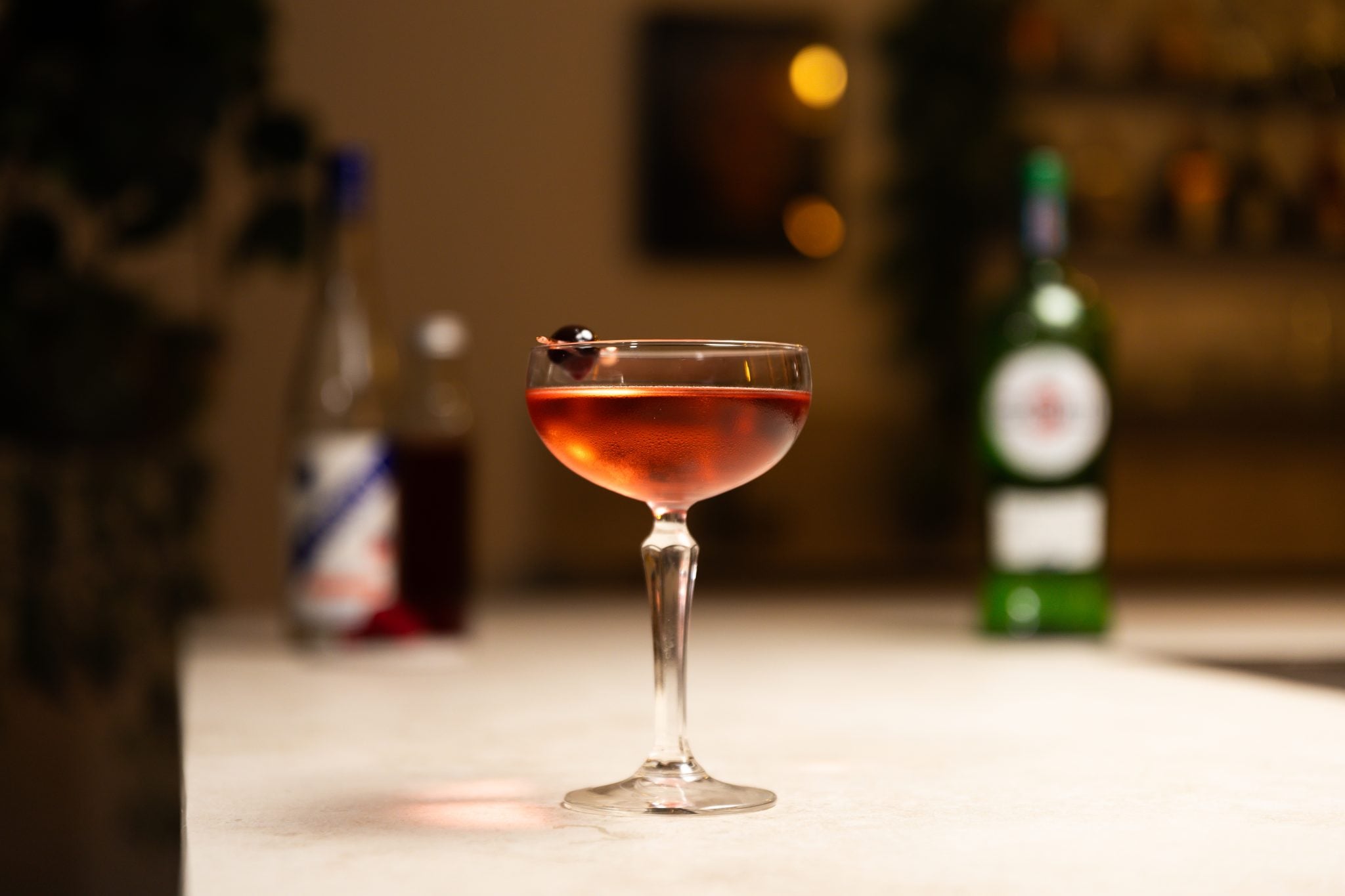 Dry vermouth, Kirsch, and raspberry syrup laid out on a white bar table