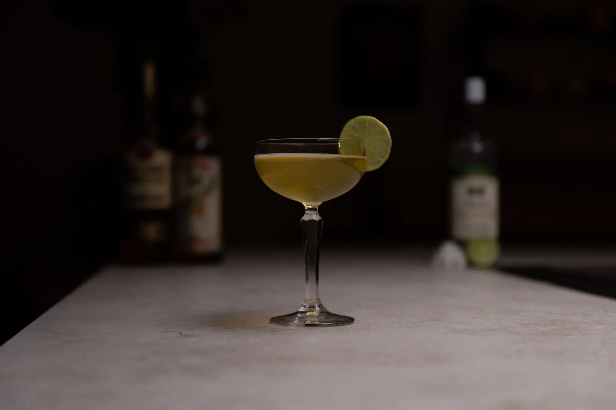 Gold rum, Falernum liqueur, orange curaçao, lime and sugar cubes laid out on a white bar table