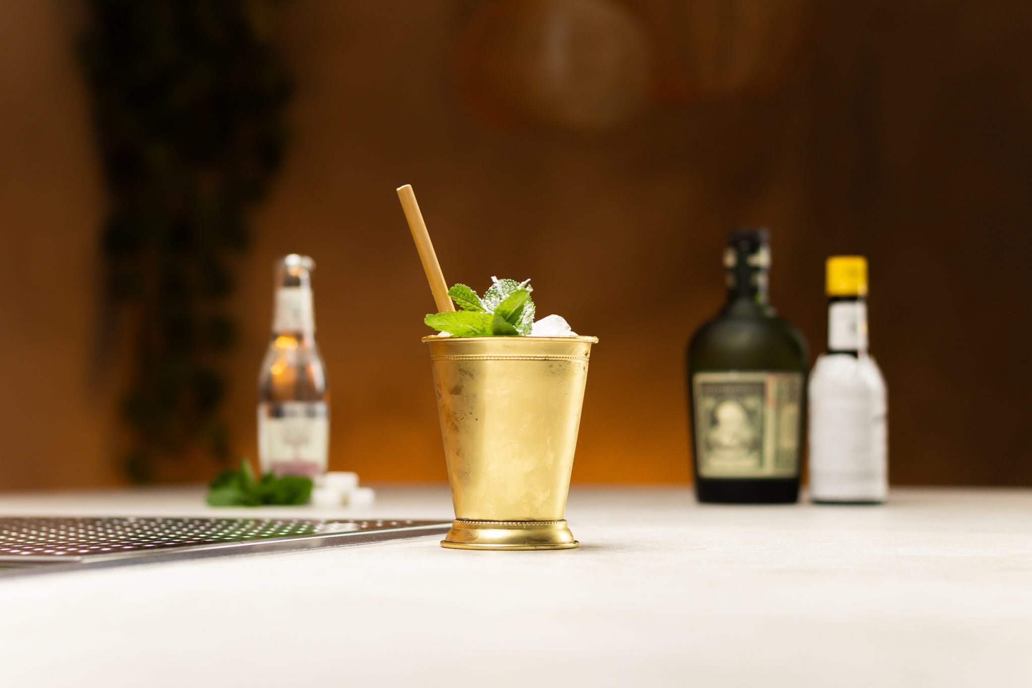 Dark Rum, mint leaves, sugar cubes, Angostura aromatic bitters, and soda water laid out on a white bar table