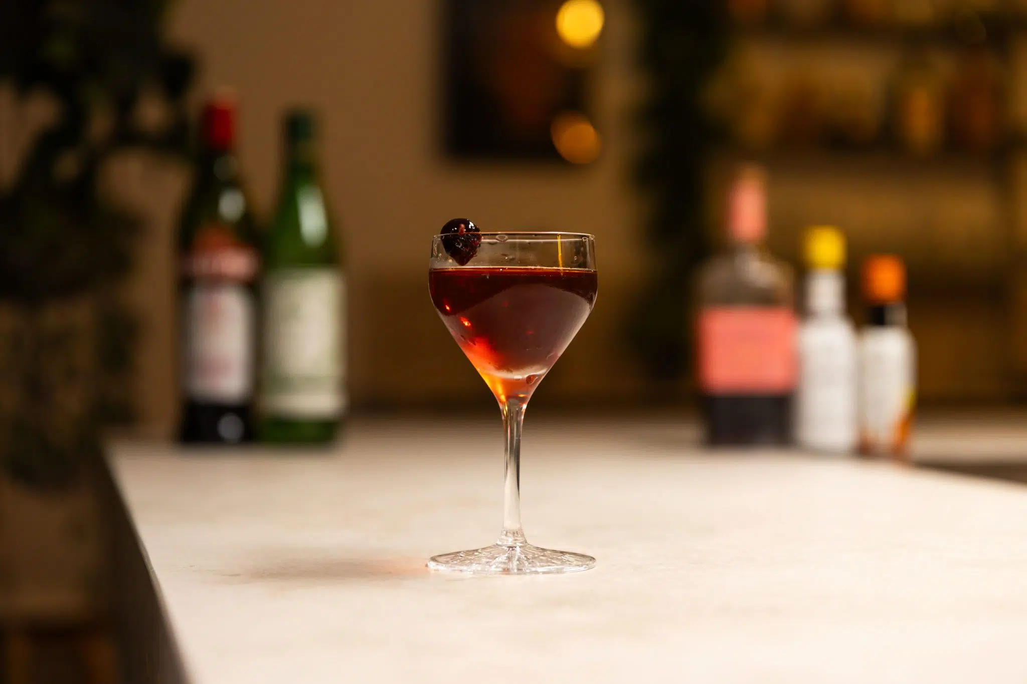 Sloe Gin, dry and sweet vermouth, orange bitters and angostura aromatic bitters laid out on a white bar table