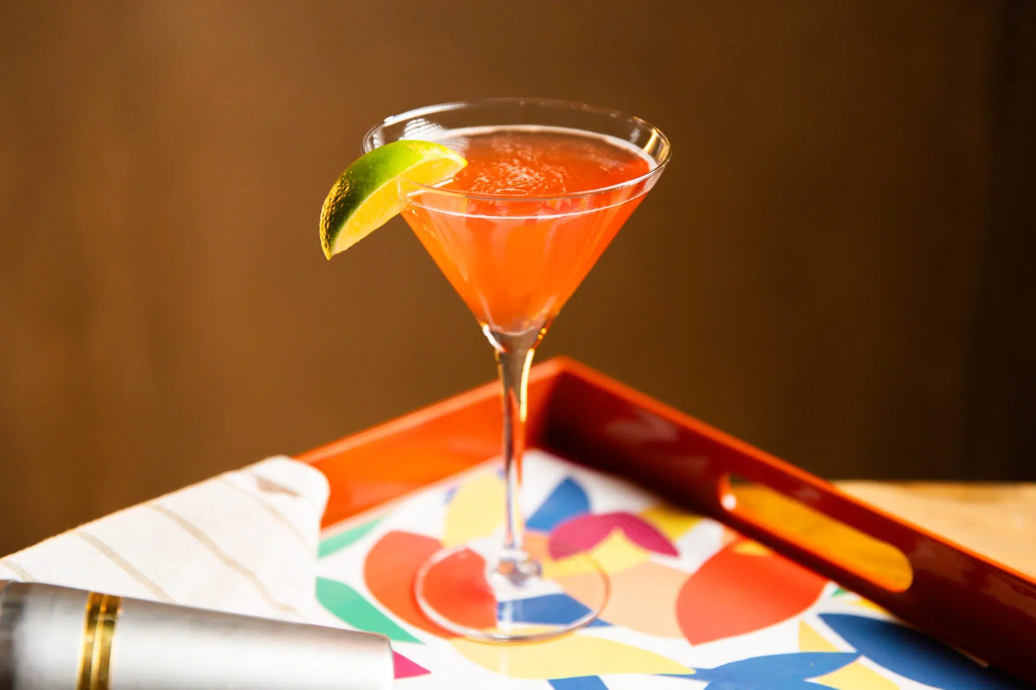 A side shot of a Scarlett O'Hara cocktail in a martini glass on a multicolor tray with a white cloth on the side