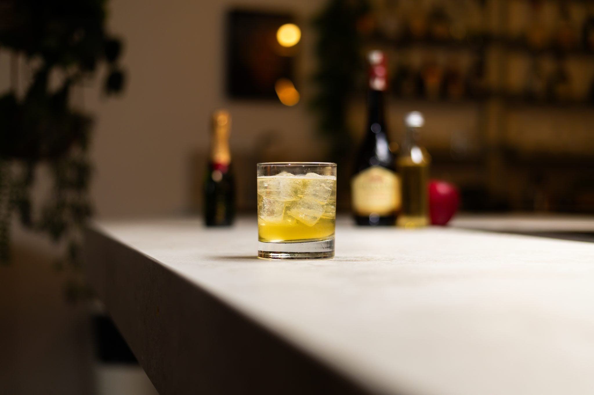 Calvados, apple juice, and champagne laid out on a white bar table